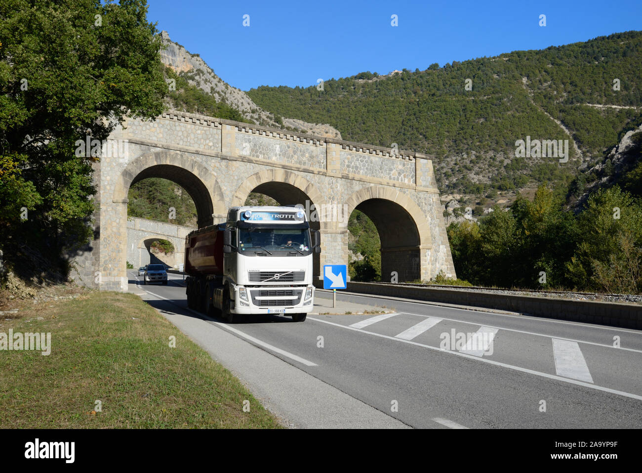 Camion roulant sous un abri de roche, un pont-pont du chenal aquatique ou un aqueduc conçu pour l'eau de la rivière Channel et un débordement sur la route pour empêcher les inondations de Fence Banque D'Images Camion roulant sous un abri de roche, un pont-pont du chenal aquatique ou un aqueduc conçu pour l'eau de la rivière Channel et un débordement sur la route pour empêcher les inondations de Fence Banque D'Images