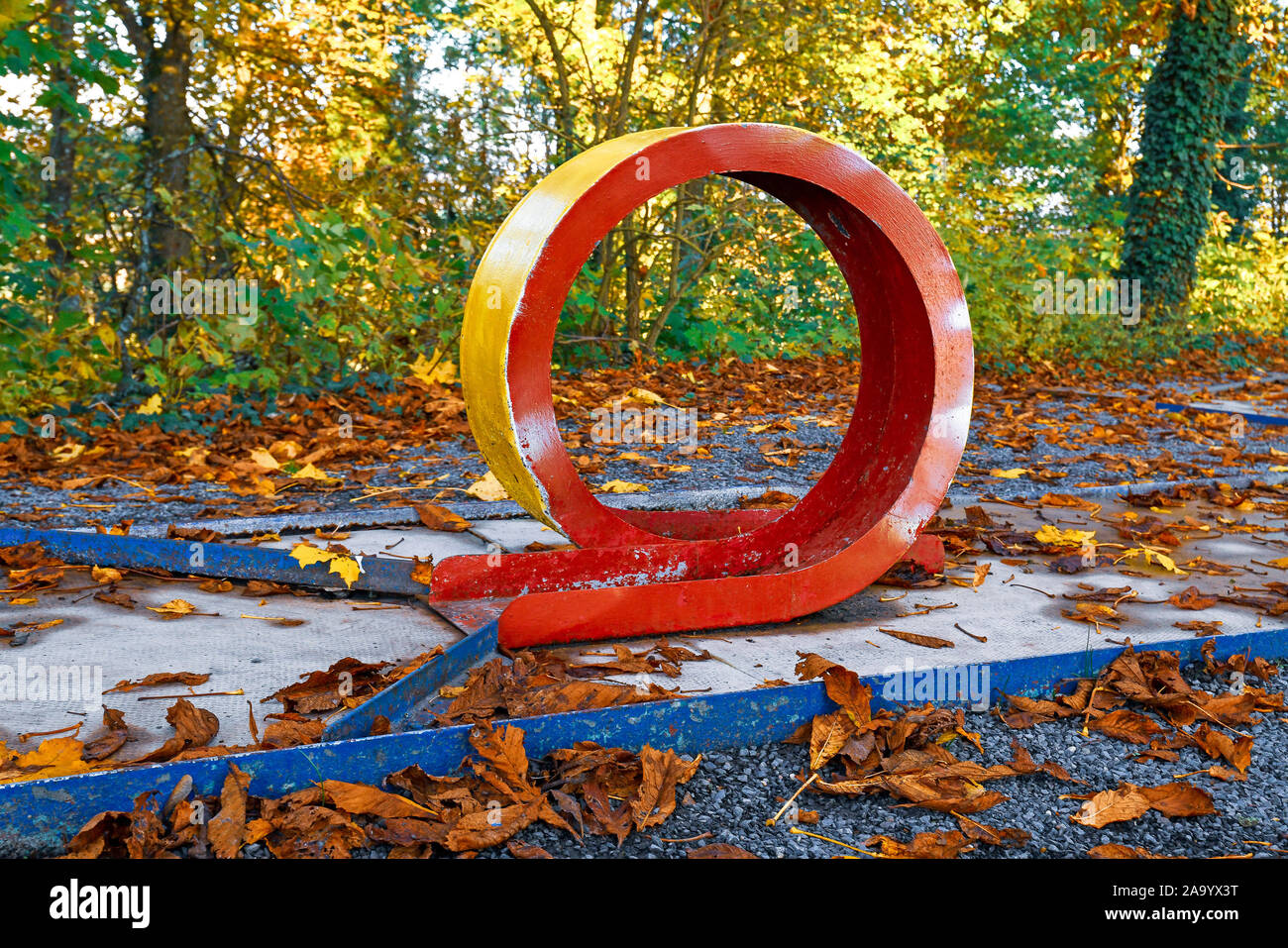 Vieux l'abandon de golf miniature avec la boucle et très ébréché de la peinture rouge recouvert de feuilles d'automne jaune Banque D'Images