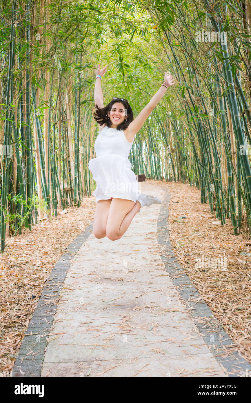 Vue avant de sauter smiling girl sur chemin de bambou. Banque D'Images