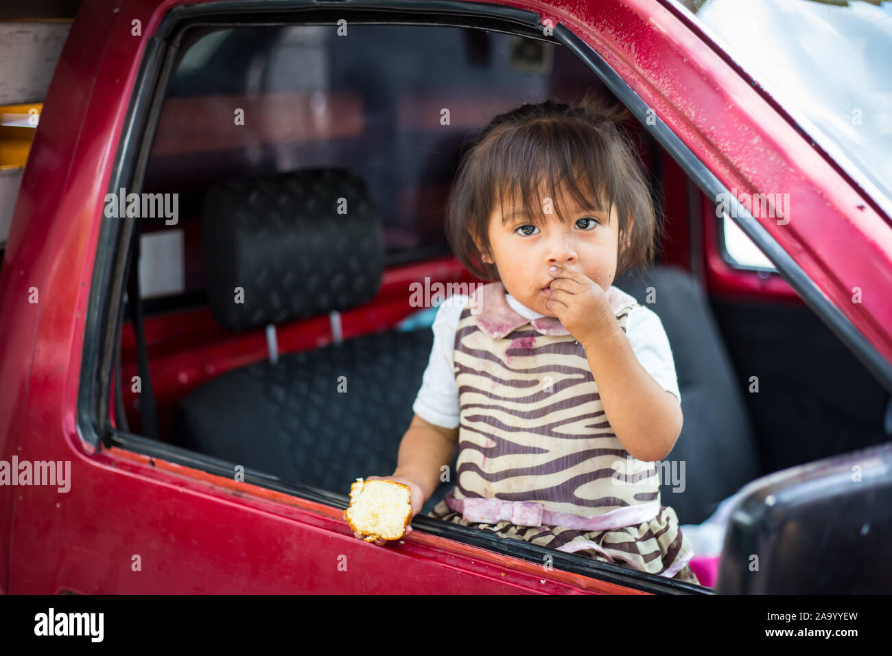 La pauvreté, portrait d'une pauvre petite fille africaine perdu dans des pensées profondes de manger du pain. Banque D'Images