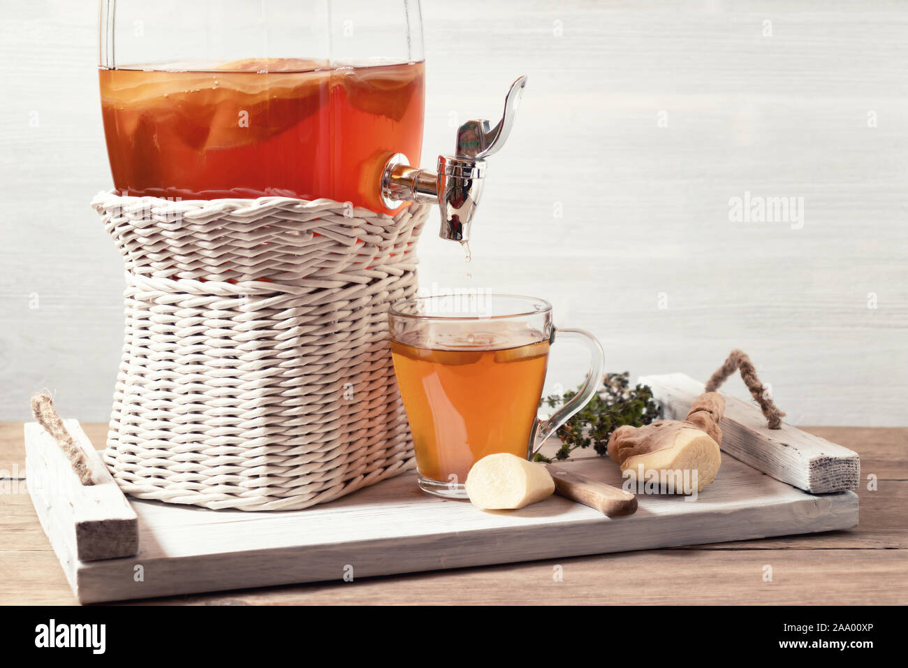 Des kombucha fermenté verre dans un pot avec robinet et dans une tasse sur un plateau blanc sur un fond de bois, copyspace. Banque D'Images