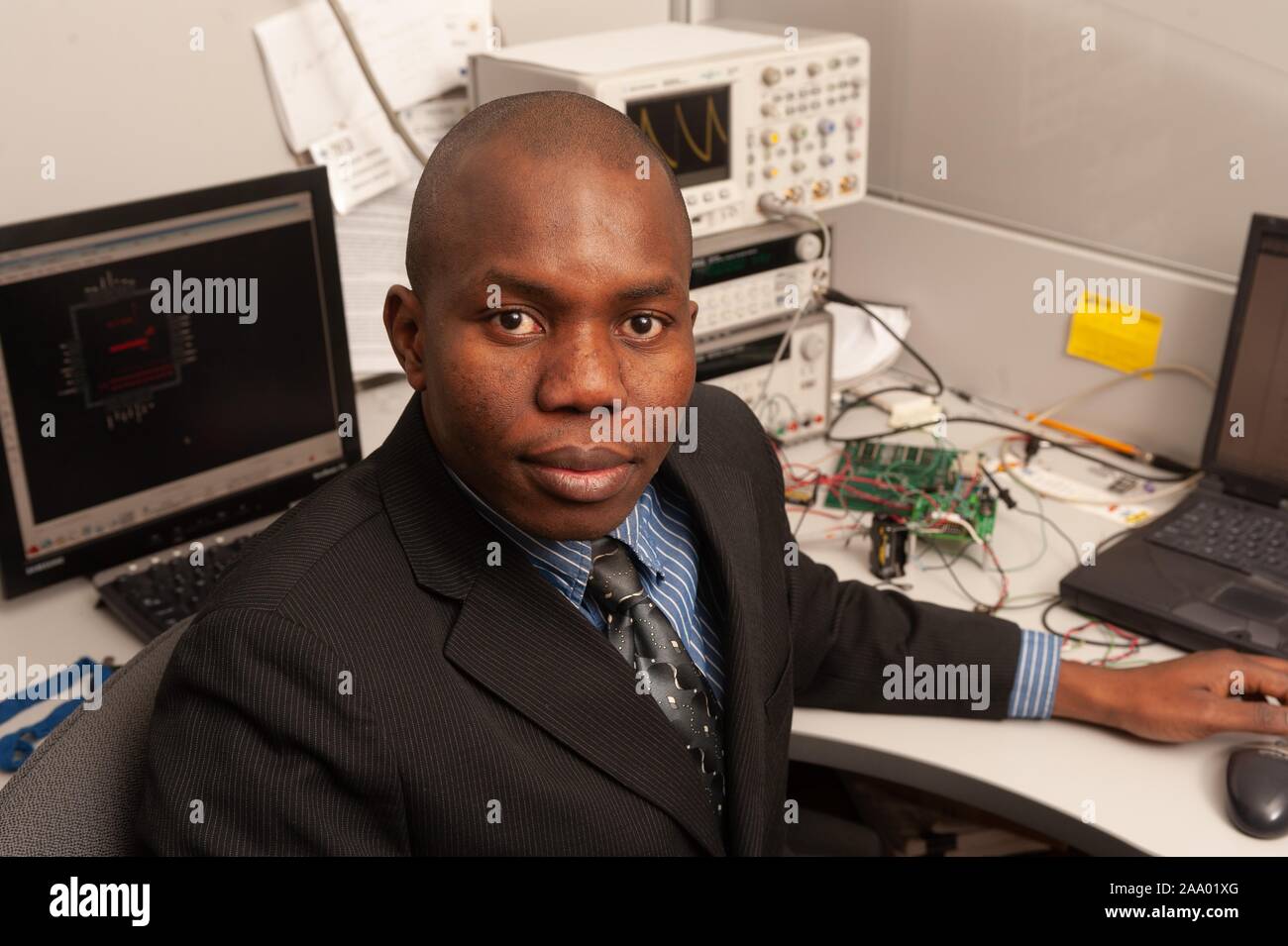 Un grand angle shot de l'ingénieur et inventeur Ndubuisi Ekekwe, assis à un bureau avec ordinateur et l'équipement électronique et se tourna face à la caméra, à l'Université Johns Hopkins University, Baltimore, Maryland, le 25 février 2009. À partir de la collection photographique de Homewood. () Banque D'Images