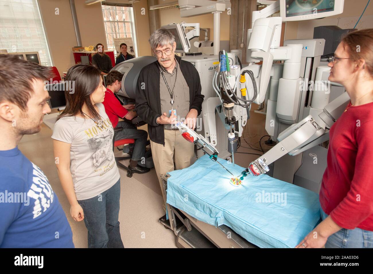 Russell Taylor, professeur d'informatique, discute avec des étudiants en génie de l'École de merlan tandis qu'un bras de robot chirurgical da Vinci travaille dans une fausse salle d'opération, à l'Université Johns Hopkins University, Baltimore, Maryland, le 6 avril 2009. À partir de la collection photographique de Homewood. () Banque D'Images