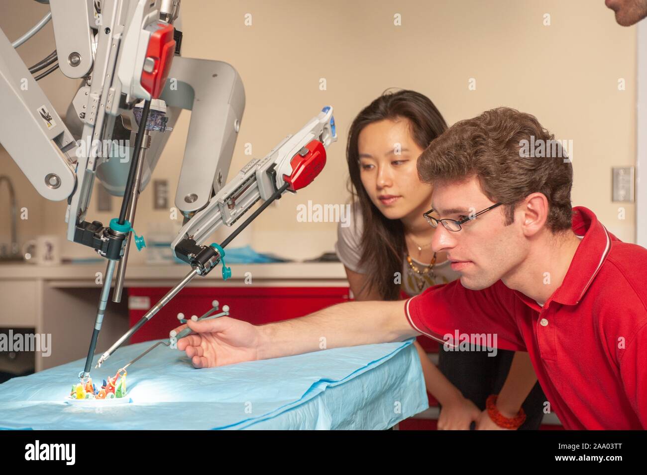 Un étudiant en génie de l'École de merlan montres un collègue utiliser un long outil pour aider un robot chirurgical da Vinci travaillant dans une fausse salle d'opération à la Johns Hopkins University, Baltimore, Maryland, le 6 avril 2009. À partir de la collection photographique de Homewood. () Banque D'Images