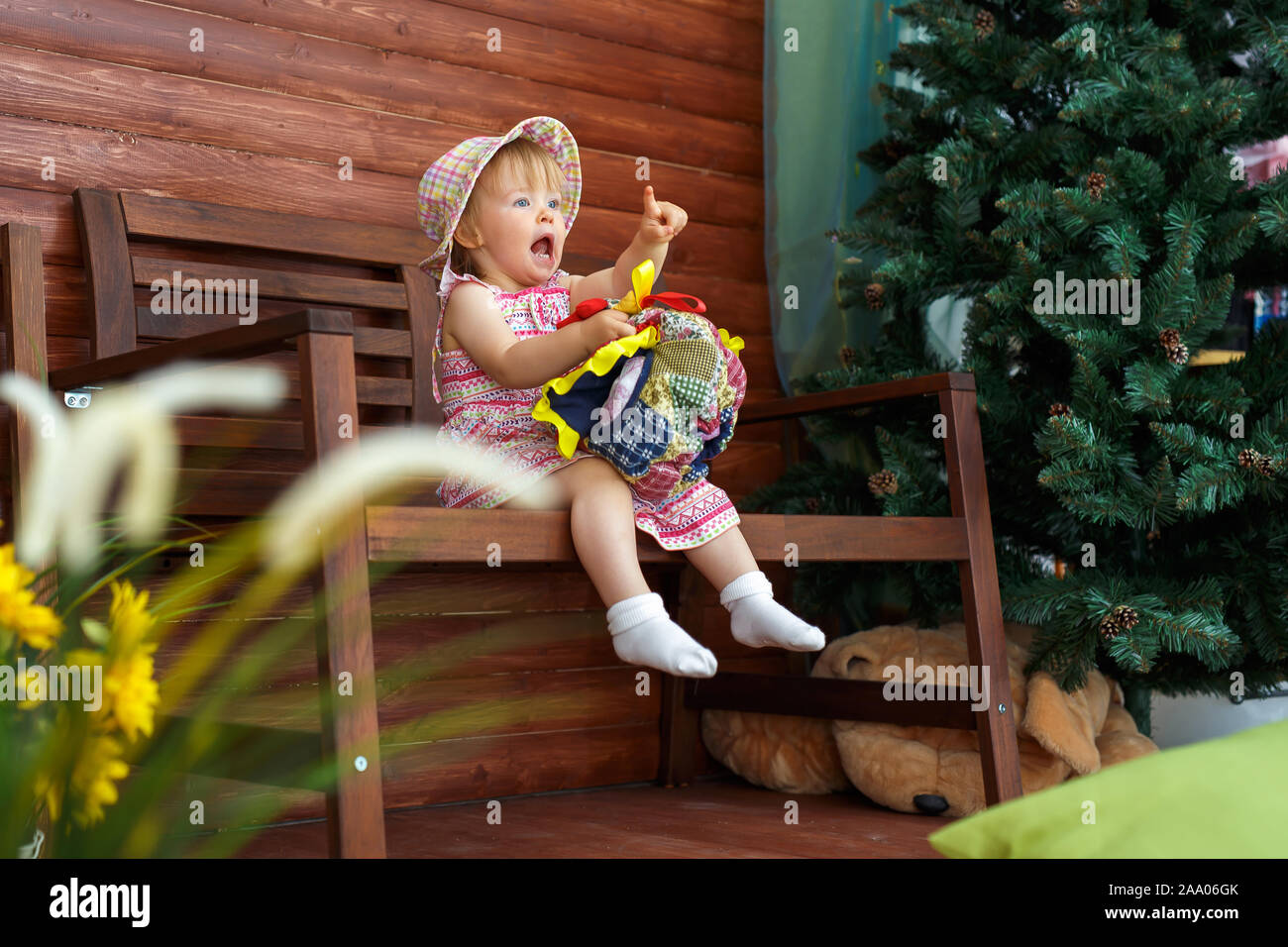 La petite fille est assise sur un grand banc et souriant. Banque D'Images