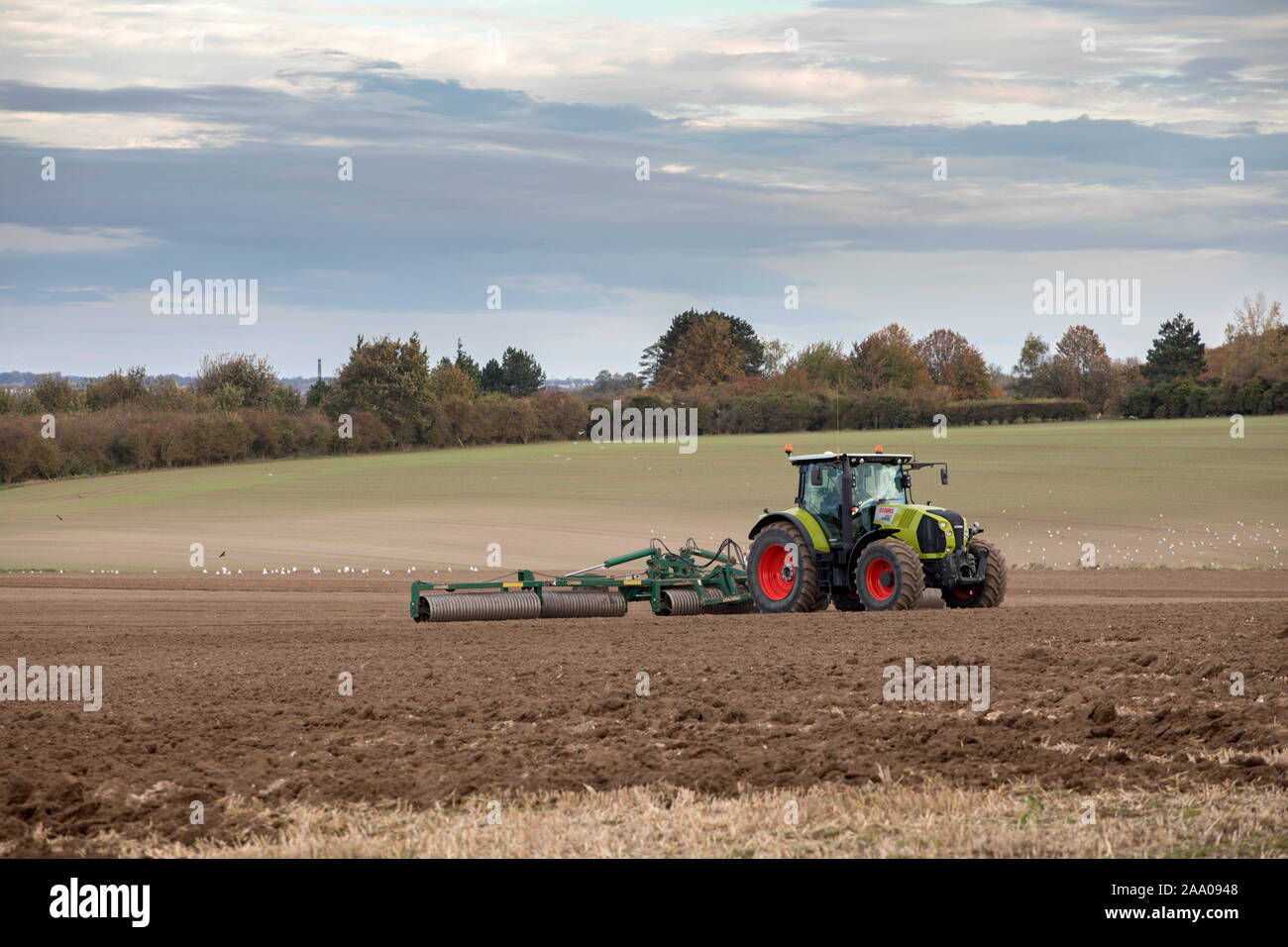 Les champs de labourage de tracteurs à la périphérie de Cambridge avec Addenbrookes hôpital au loin Banque D'Images