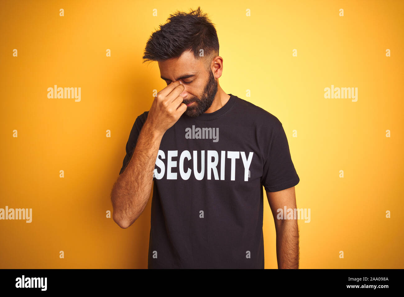 Sauvegarde hispanique indienne arabe homme portant un uniforme de sécurité sur fond jaune isolé fatigué se frottant le nez et les yeux sentant la fatigue et les céphalées. Banque D'Images