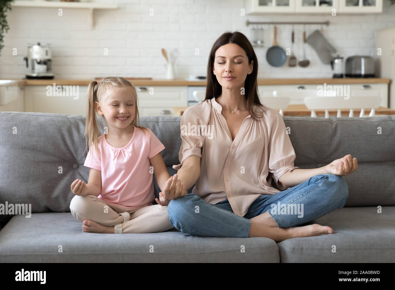 30s woman sitting in lotus pose avec jolie petite fille. Banque D'Images