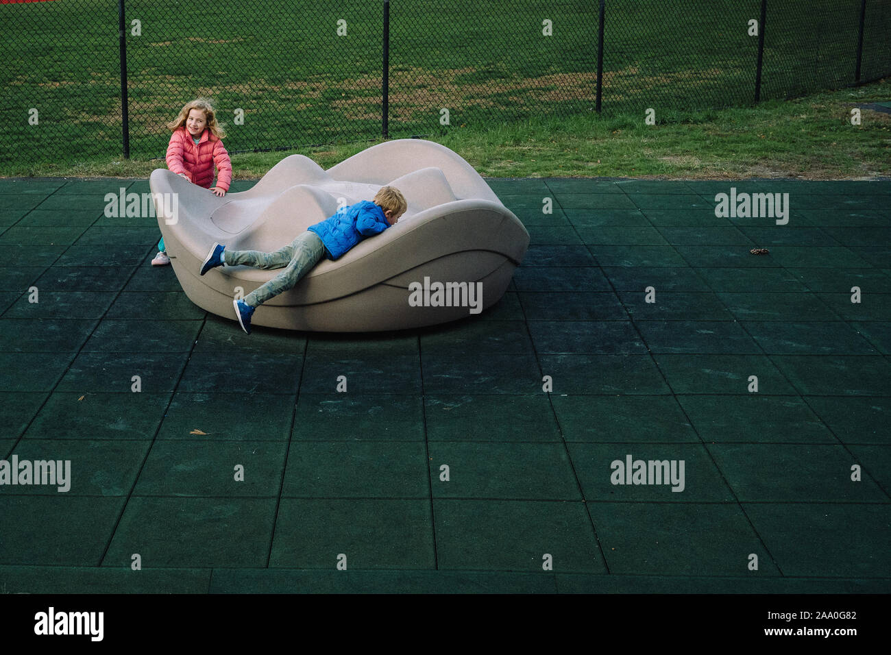 Deux enfants jouent sur un manège à une aire de jeux. Banque D'Images