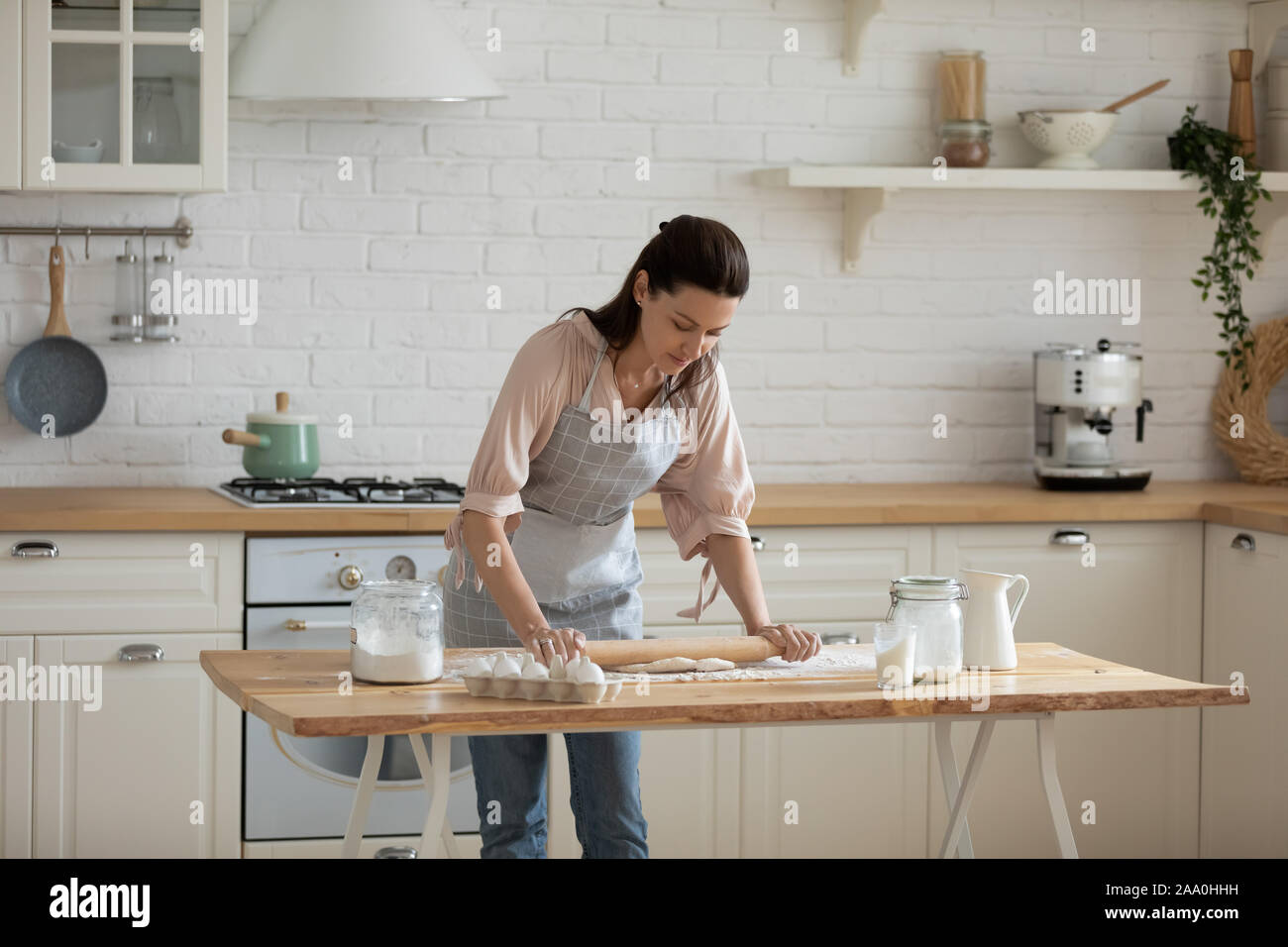 30s femme penché au-dessus de table, rouler la pâte. Banque D'Images