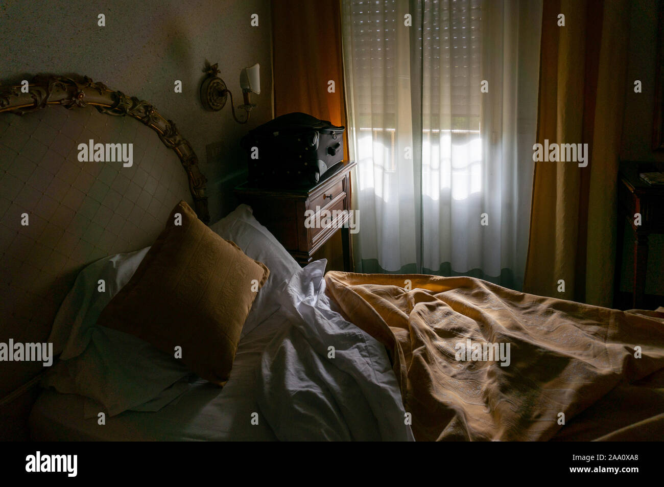 Lit défait dans la chambre d'hôtel avec matin lumière provenant d'une fenêtre, Pise Italie Banque D'Images