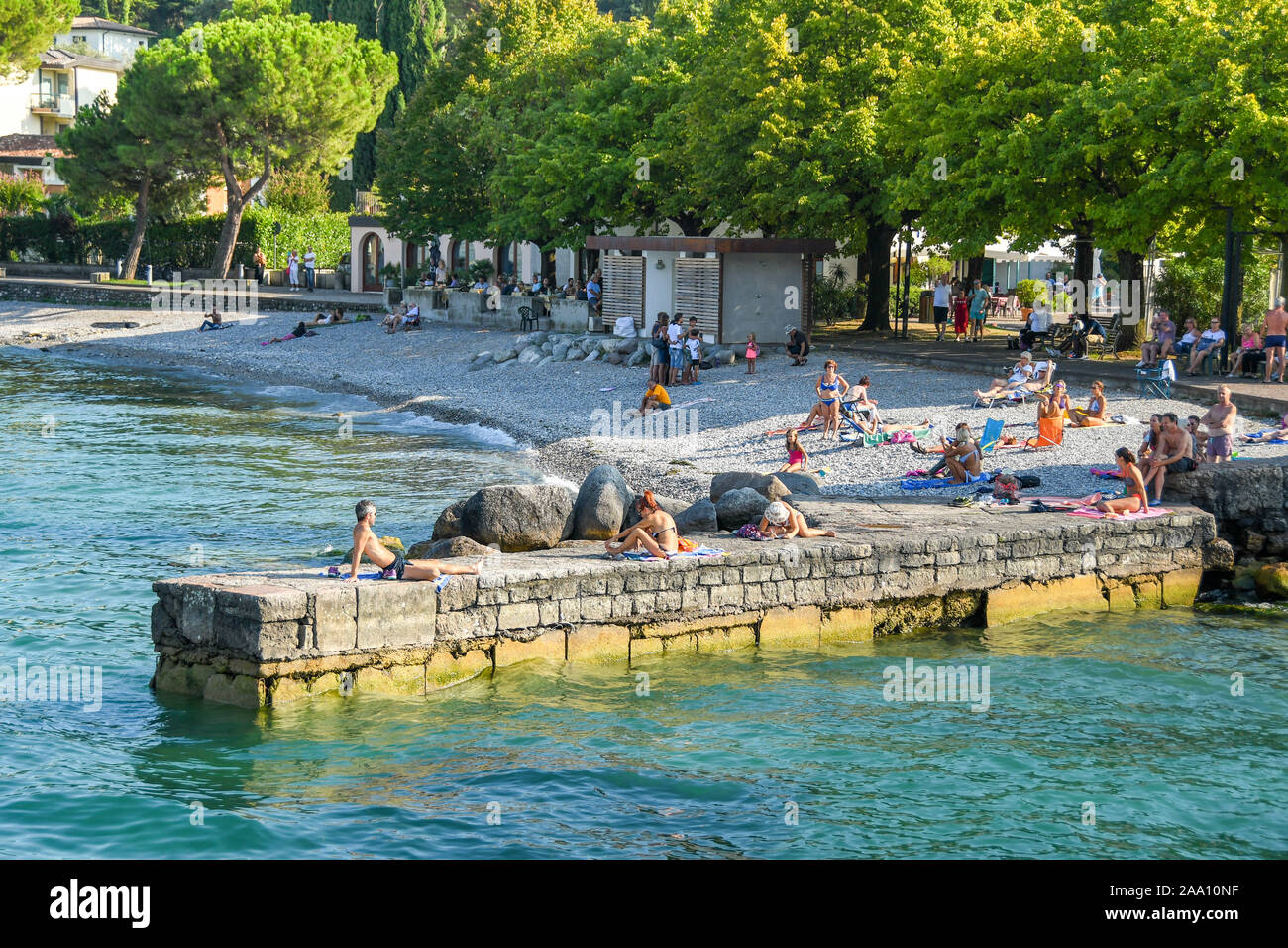 PORTESE, ITALIE - Septembre 2018 : les gens à prendre le soleil sur la pierre jetée dans la station de Portese sur le lac de Garde. Banque D'Images