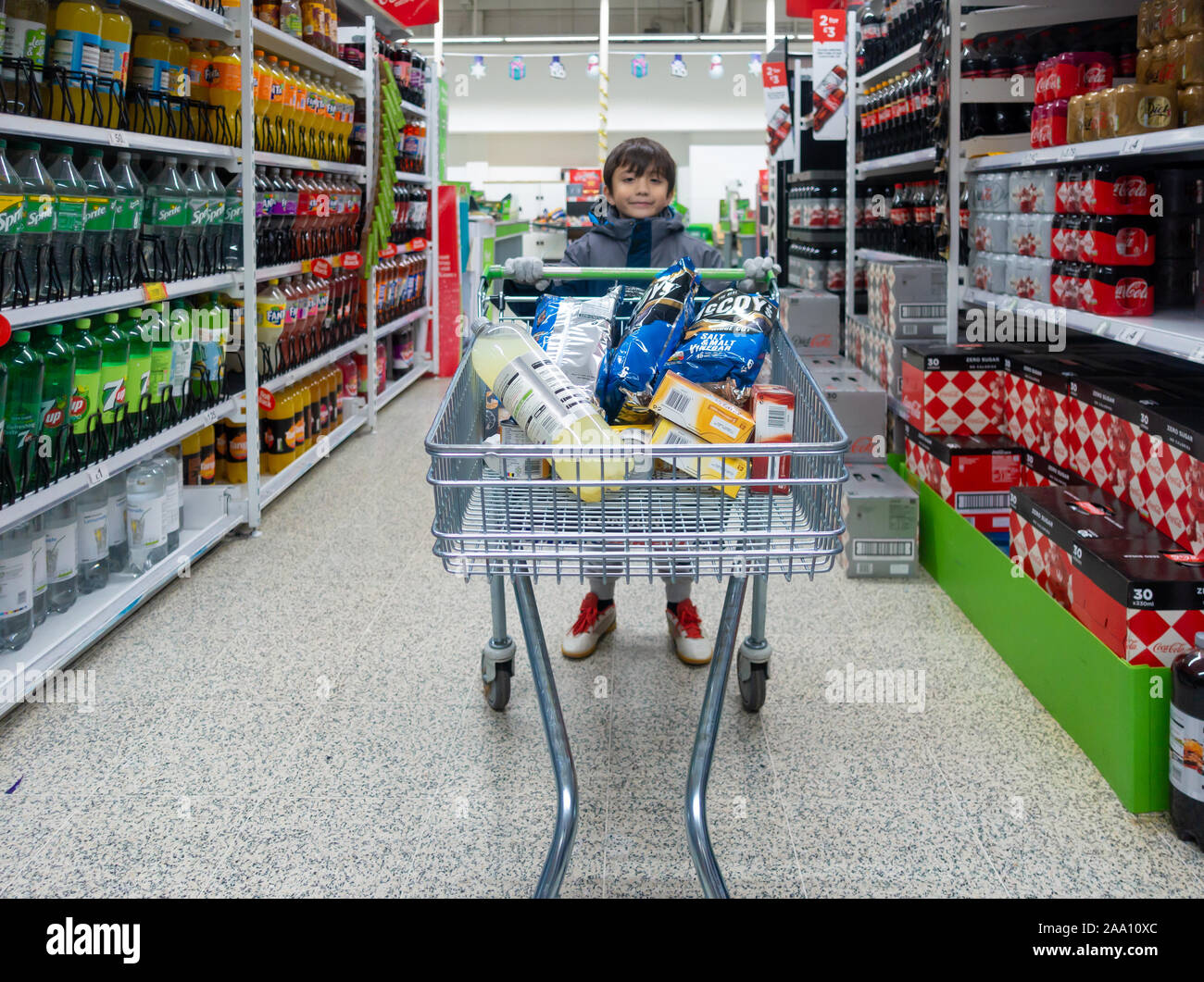 Un jeune garçon pousse un chariot dans un supermarché Banque D'Images