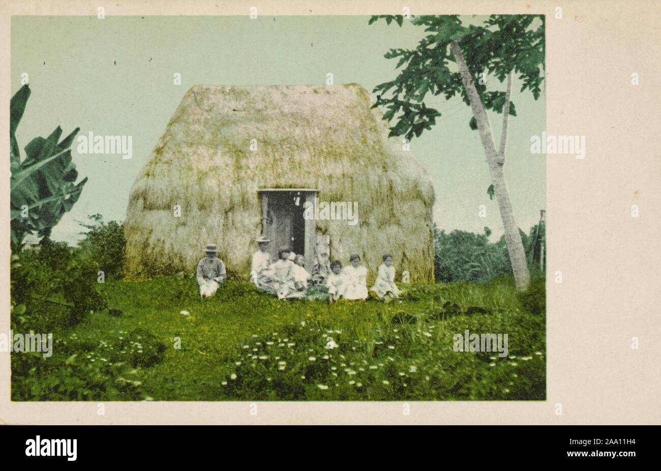 Carte postale illustrée d'une famille assise sur l'herbe en face de nipa hut en chaume, dans une zone rurale aux Philippines, 1905. À partir de la Bibliothèque publique de New York. () Banque D'Images