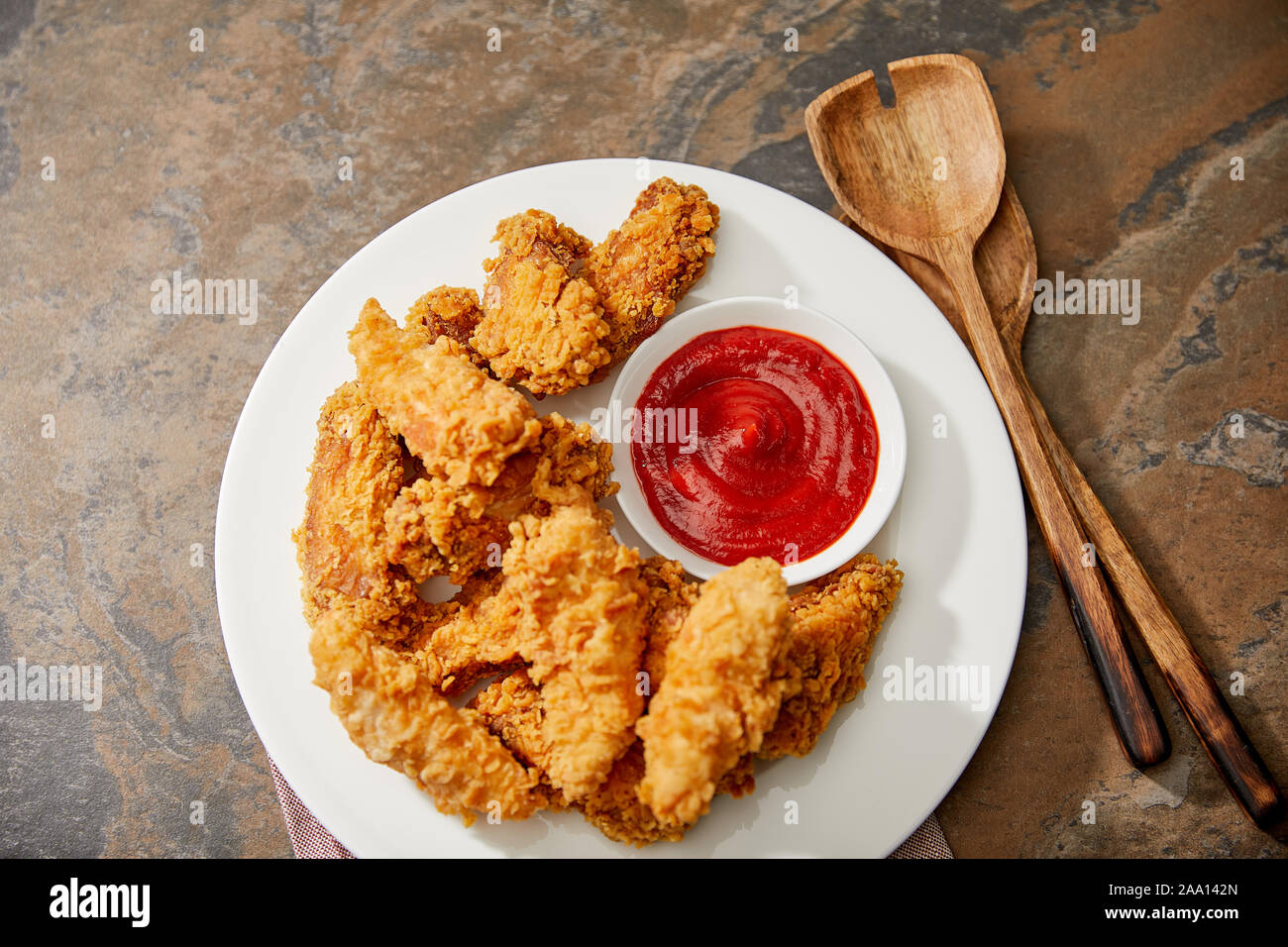 Vue de dessus de délicieux nuggets de poulet avec du ketchup et spatules en bois sur la surface de pierre Banque D'Images