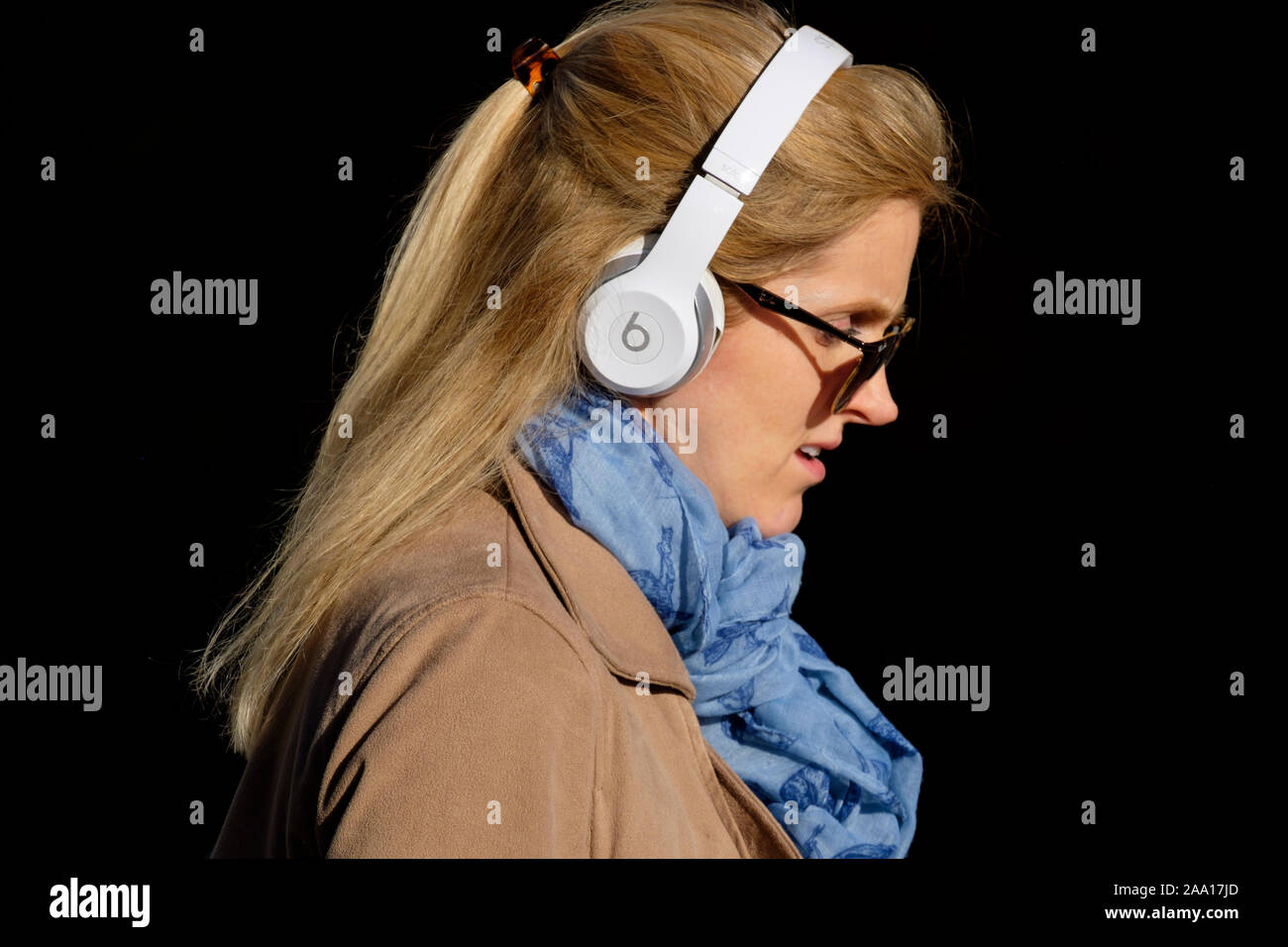 Femme, 20 ans, cheveux blonds, robe élégante et tendance, foulard, écouteurs Beats sur London Street. Banque D'Images
