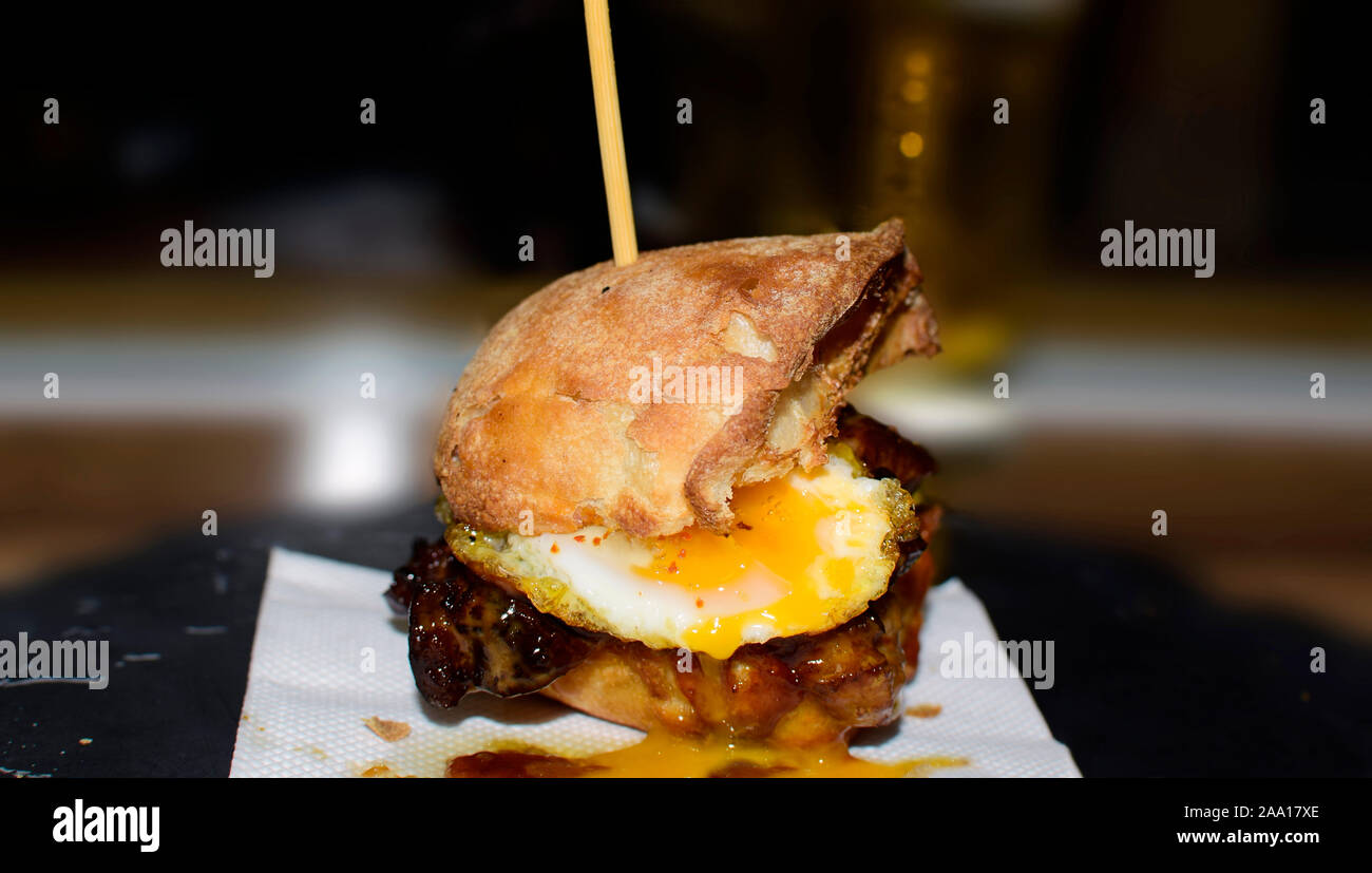 Close up mini burger de bœuf Angus grillé, bacon, fromage, oeufs de caille au plat, et les sauces à la crème sur fond de bois et papier thecraft. Banque D'Images