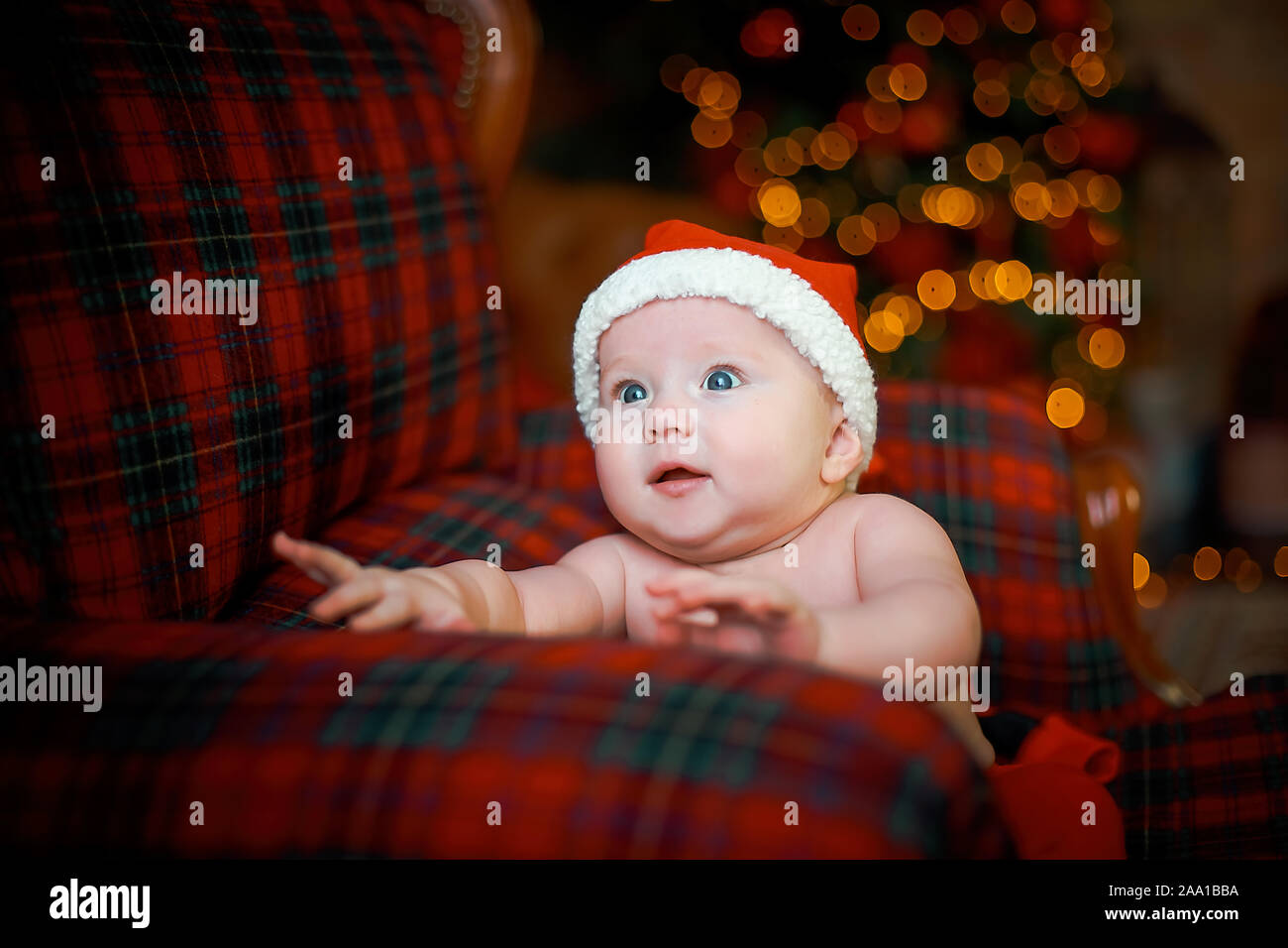 Happy Child In Santa Hat Pres De Cadeaux Sur Fond De Nouvel An Des Arbres Dans La Salle Des Fetes 6 Mois Bebe Est Souriant Belle Petite Fille En Attente De Chr
