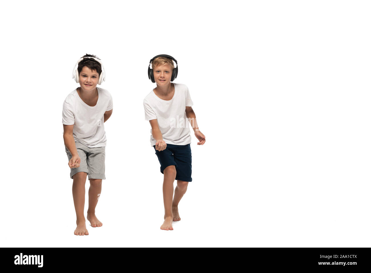 Deux frères à la caméra et à danser tout en écoutant la musique au casque sur fond blanc Banque D'Images