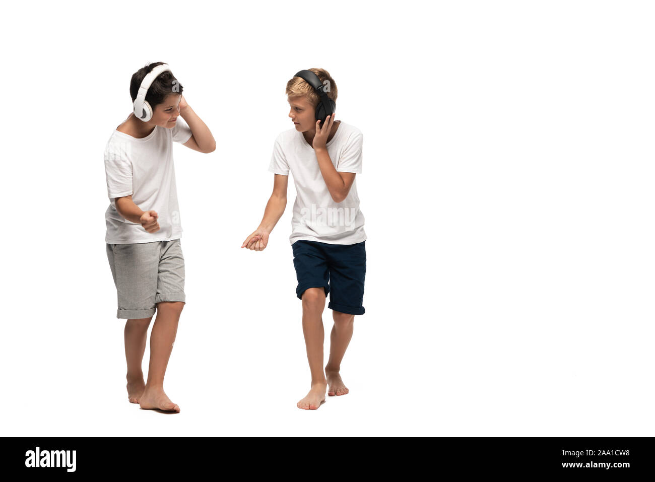 Deux frères à l'écoute au casque de la musique et de la danse sur fond blanc Banque D'Images