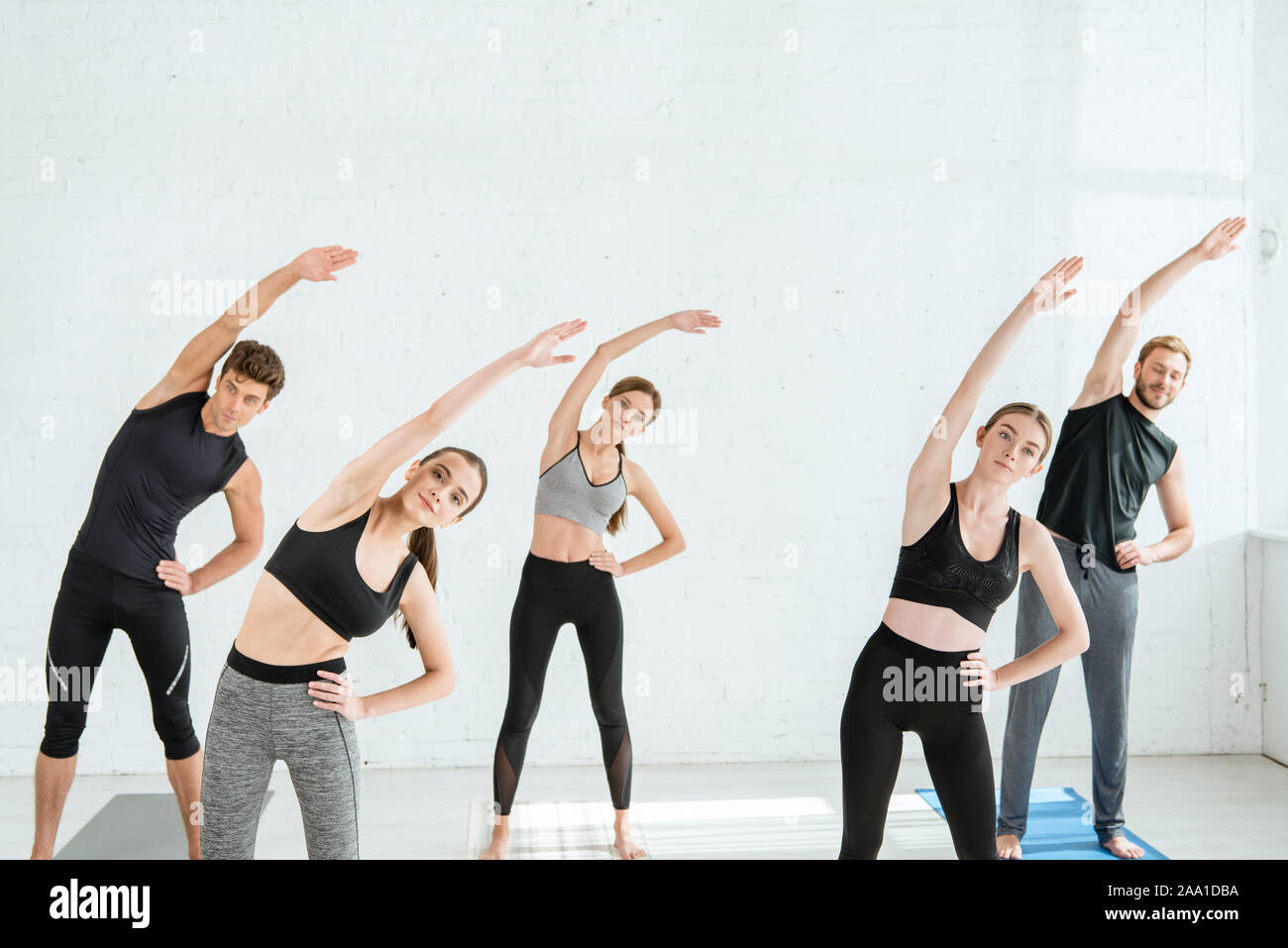 Cinq jeunes gens qui font de l'inclinaison latérale dans la posture de l'étoile with hand on hip Banque D'Images