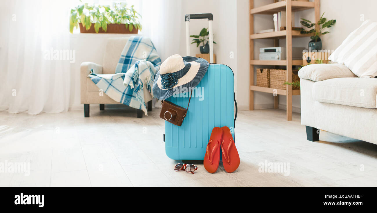 Valise bleue avec havaianas et chapeau à la maison de l'intérieur. Banque D'Images