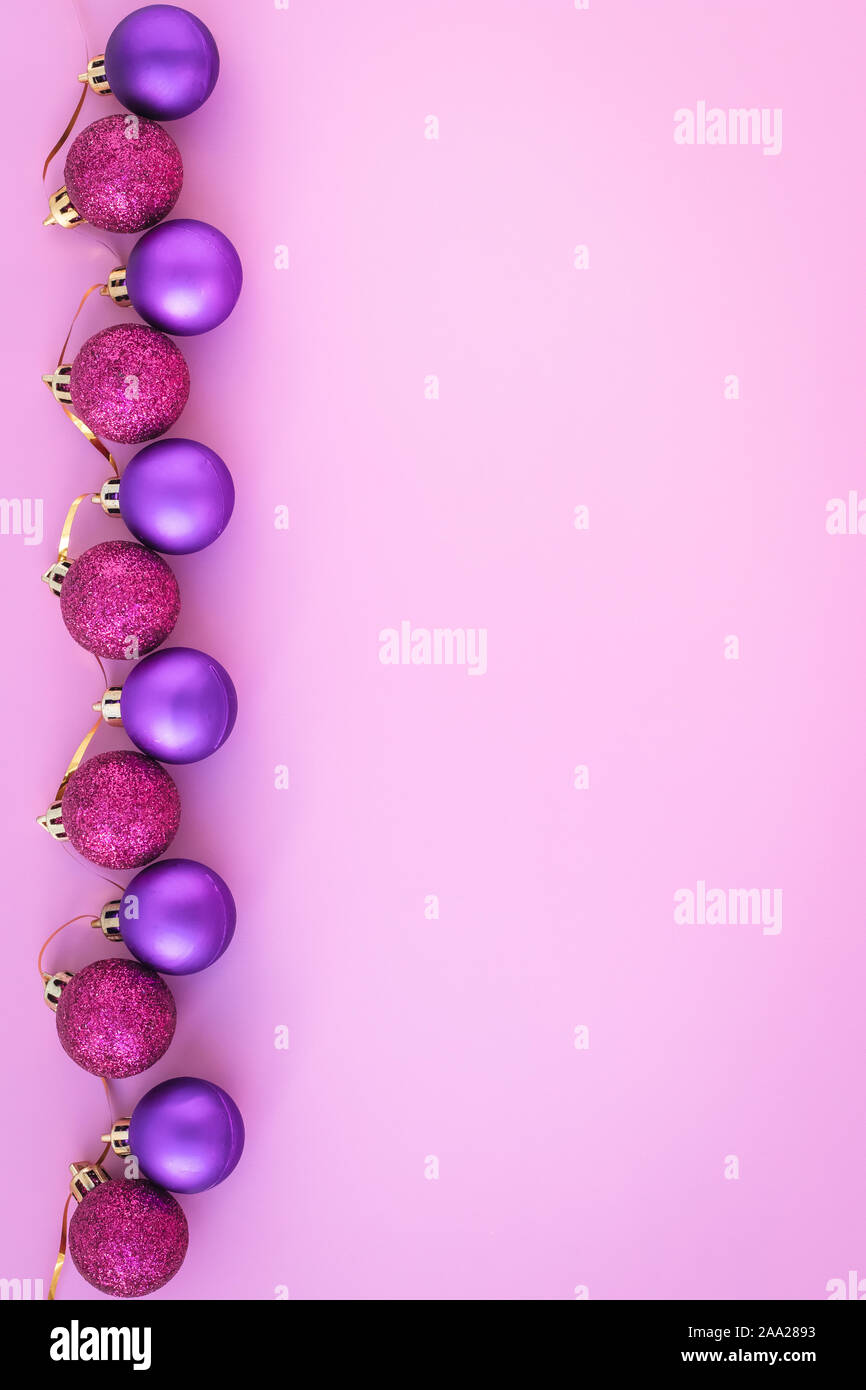 Résumé fond rose avec noël boules violettes. Carte de vœux du nouvel an avec des sphères. Mise en page avec copie espace. Minimal Art design. Banque D'Images