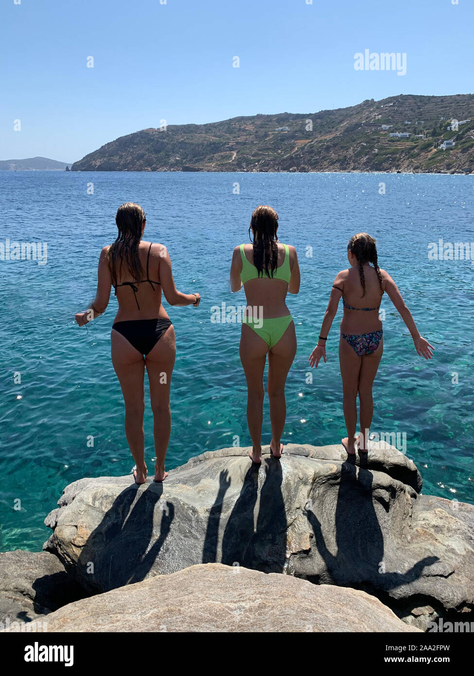 Trois jeunes filles debout sur des rochers prêt à sauter dans la mer, Grèce Banque D'Images