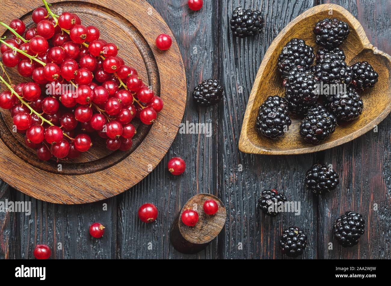 Fruit rouge et noir dans la cuisine. Groseille rouge et blackberry sur une table en bois brun. Banque D'Images