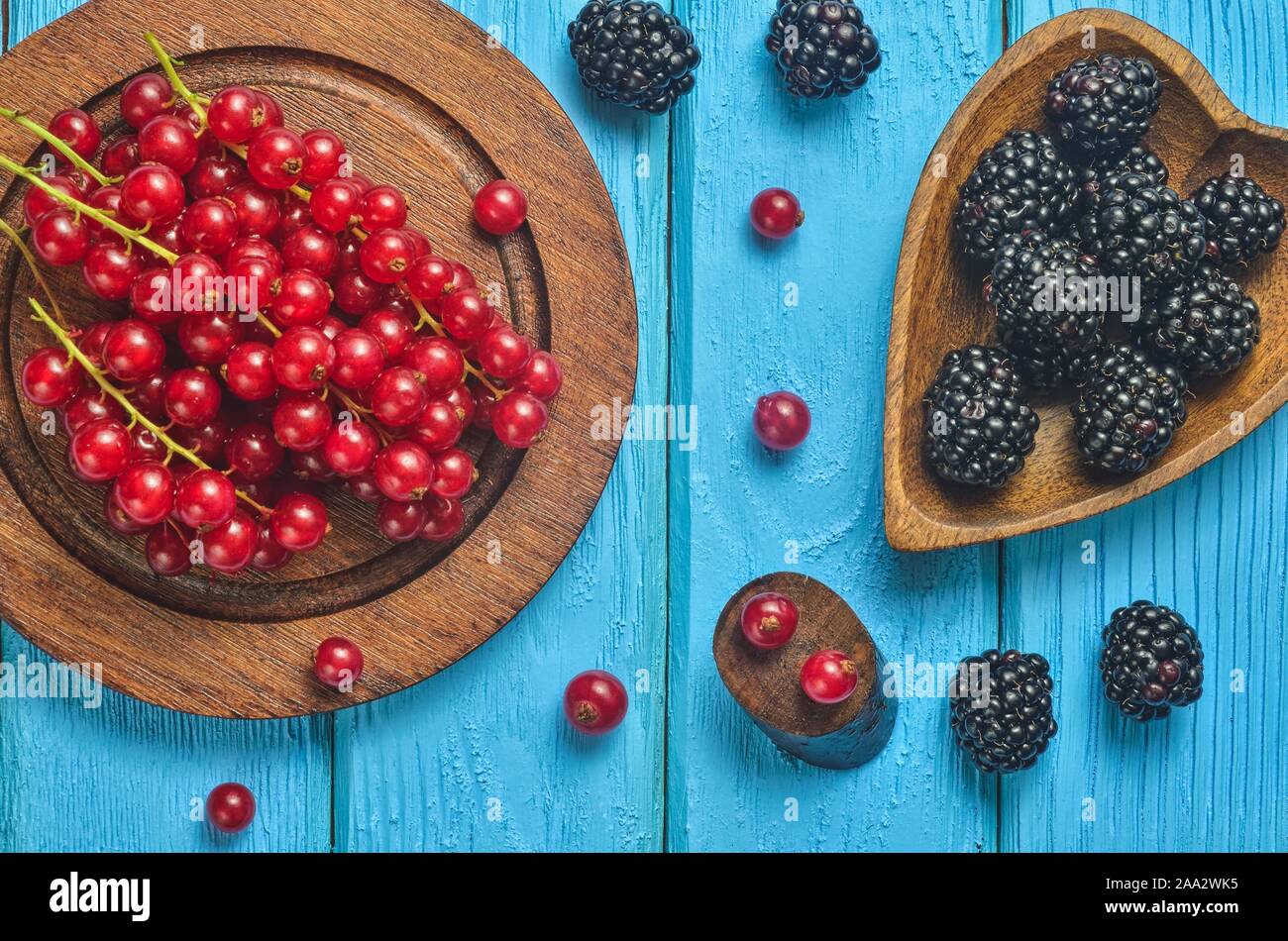 Fruit rouge et noir dans la cuisine. Groseille rouge et blackberry sur une table en bois bleu. Banque D'Images