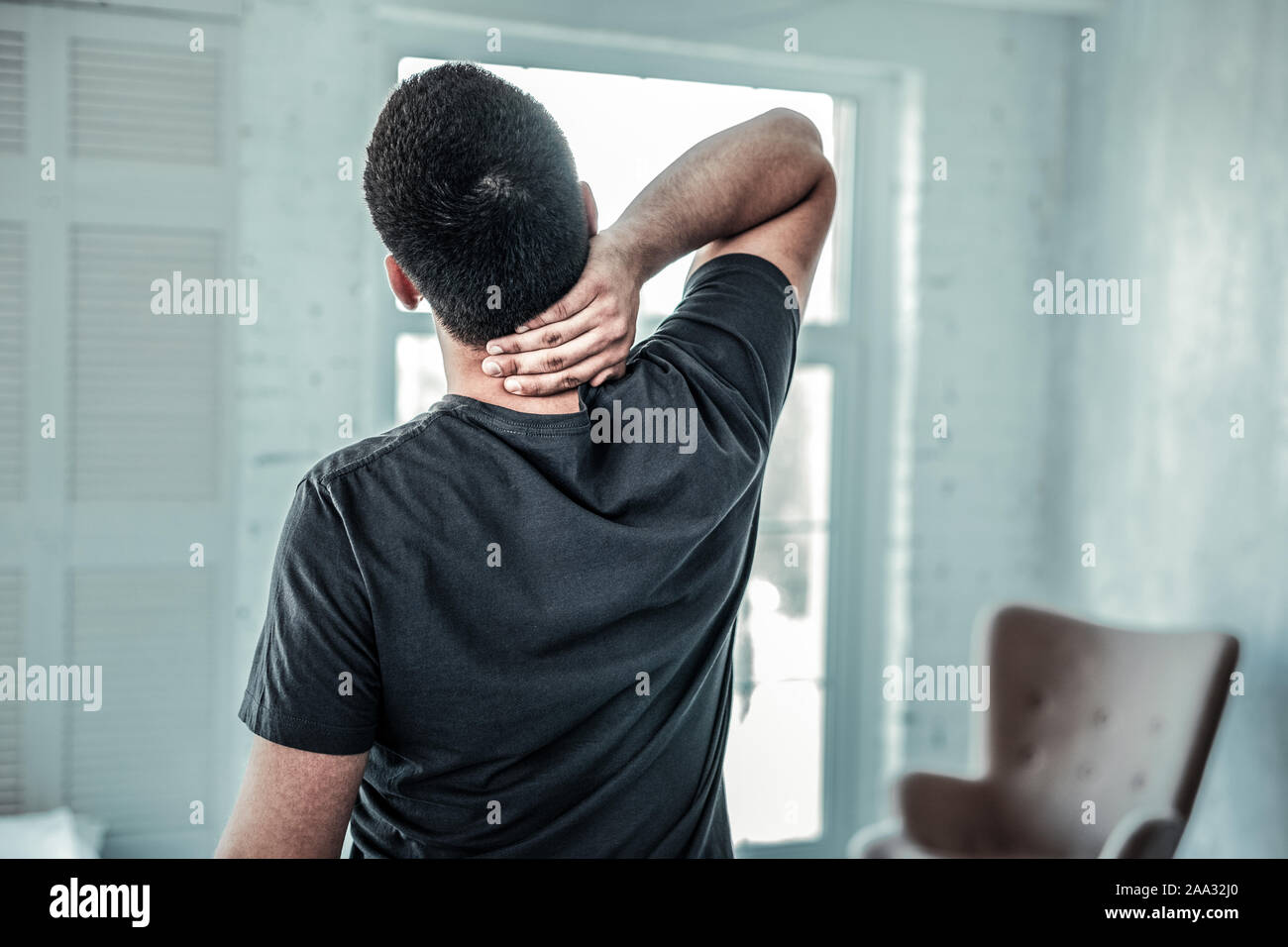 Bonne recherche Jeune homme tenant son cou Banque D'Images