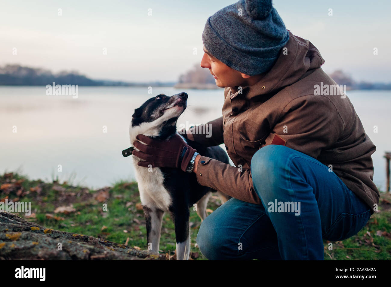 Man Walking dog in autumn park par lac. Heureux animal de s'amuser en plein air Banque D'Images