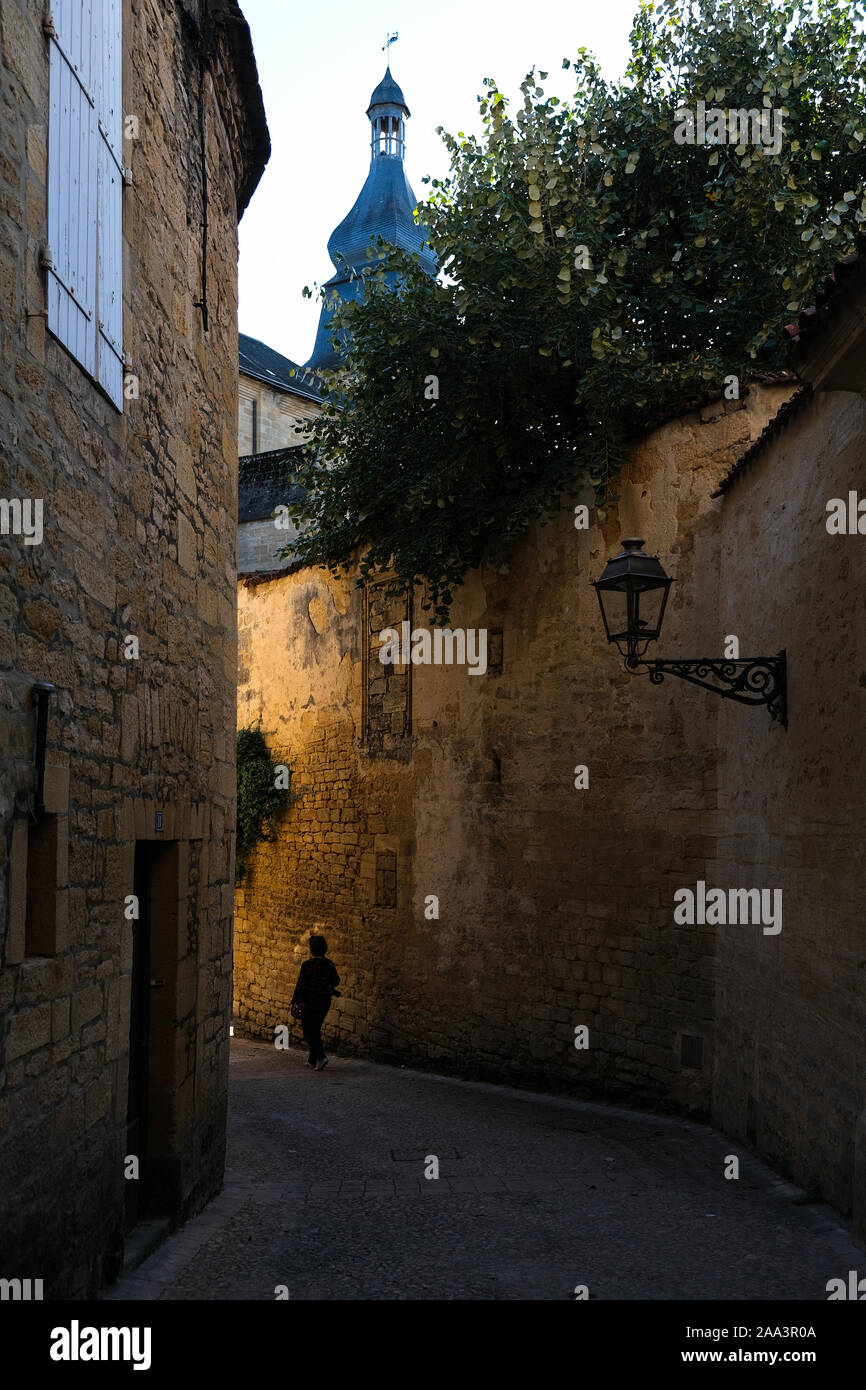 Femme marche dans une rue étroite de Sarlat-la-caneda, Aquitaine, France Banque D'Images