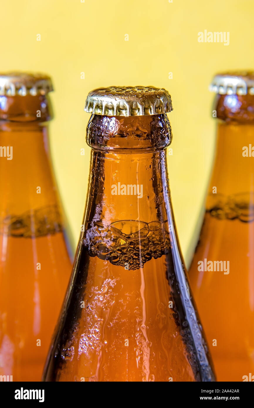Une bouteille avec verre sur fond jaune. La bière dans une bouteille de verre rosée fermé avec un couvercle. Banque D'Images