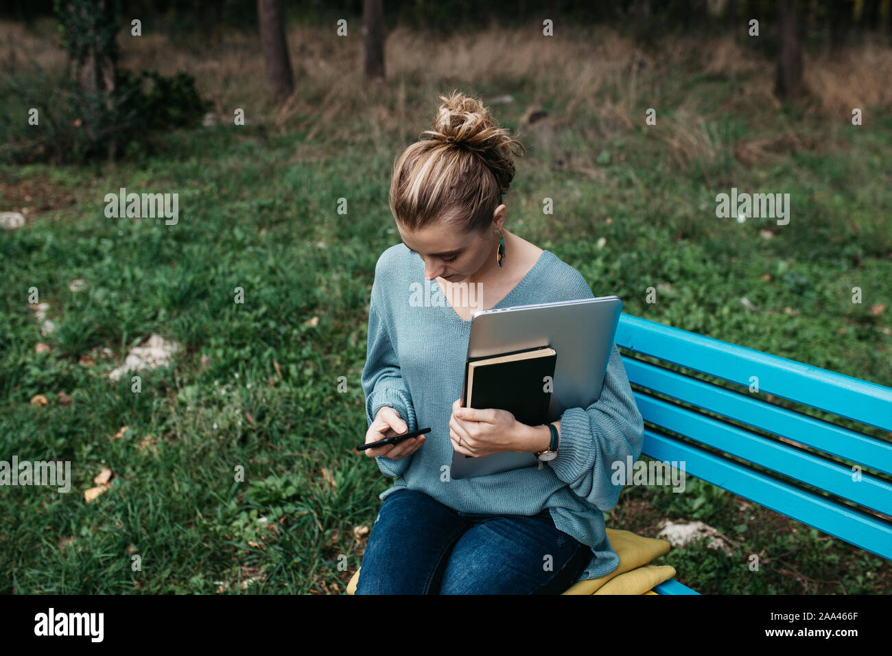 Close up of young woman de taper sur son téléphone mobile. L'espace de copie pour le texte. Elle est également tenue de livres et l'ordinateur portable. Banque D'Images