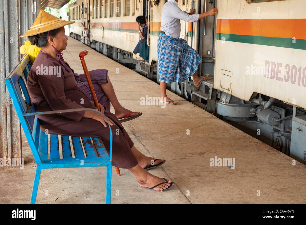 Une vieille femme birmane vêtu d'un Chapeau conique traditionnel et asiatique tenant une cane attend à bord d'un train à la gare centrale de Yangon Banque D'Images