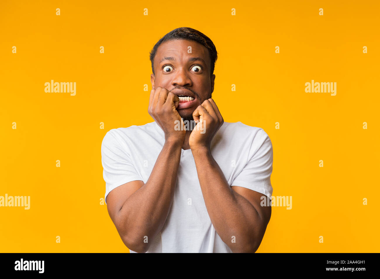 Guy Afro peur toucher Face posant sur fond jaune Banque D'Images