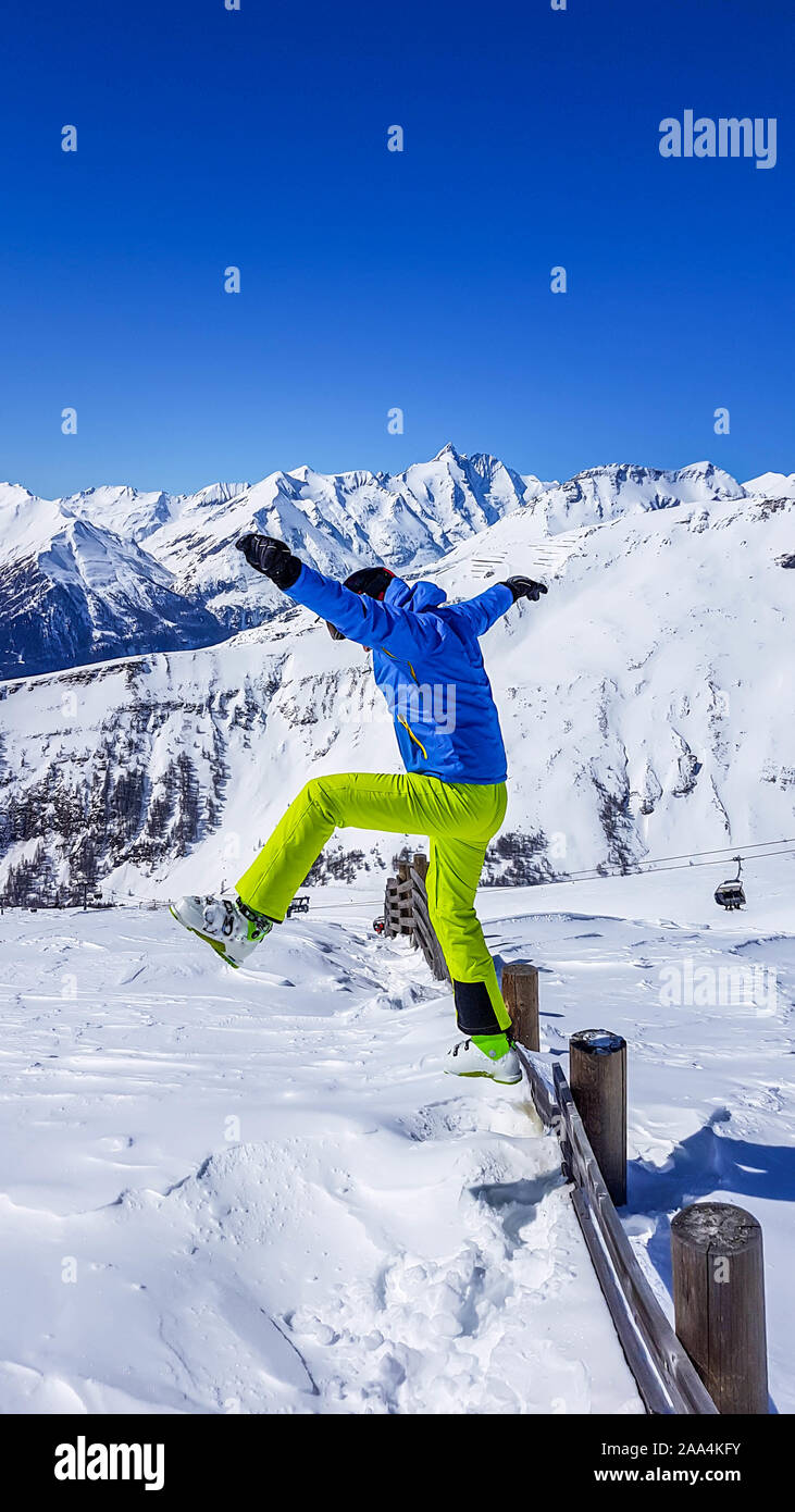 L'homme dans une tenue de ski de sauter dans la neige fraîche. Homme porte  veste bleue et pantalon vert fluo. Beaucoup de poudreuse fraîche autour de  lui. Pe Haut Photo Stock -