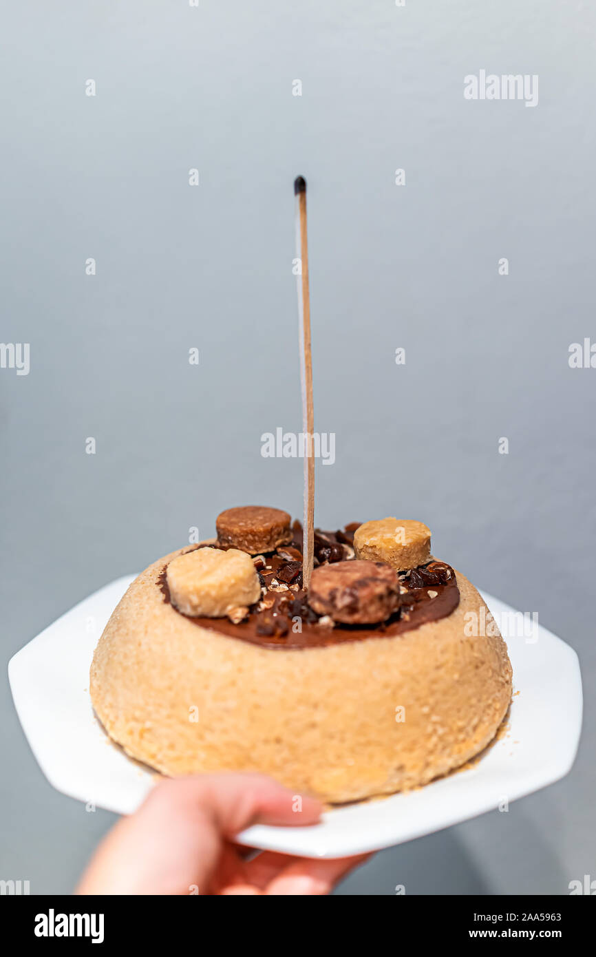 Main Tenant Une Jaune Dessert Vanille Gateau Au Chocolat Fait Maison Avec Du Glacage Et Decoration Bougie Macaron Avec Match Stick Pour Anniversaire Photo Stock Alamy