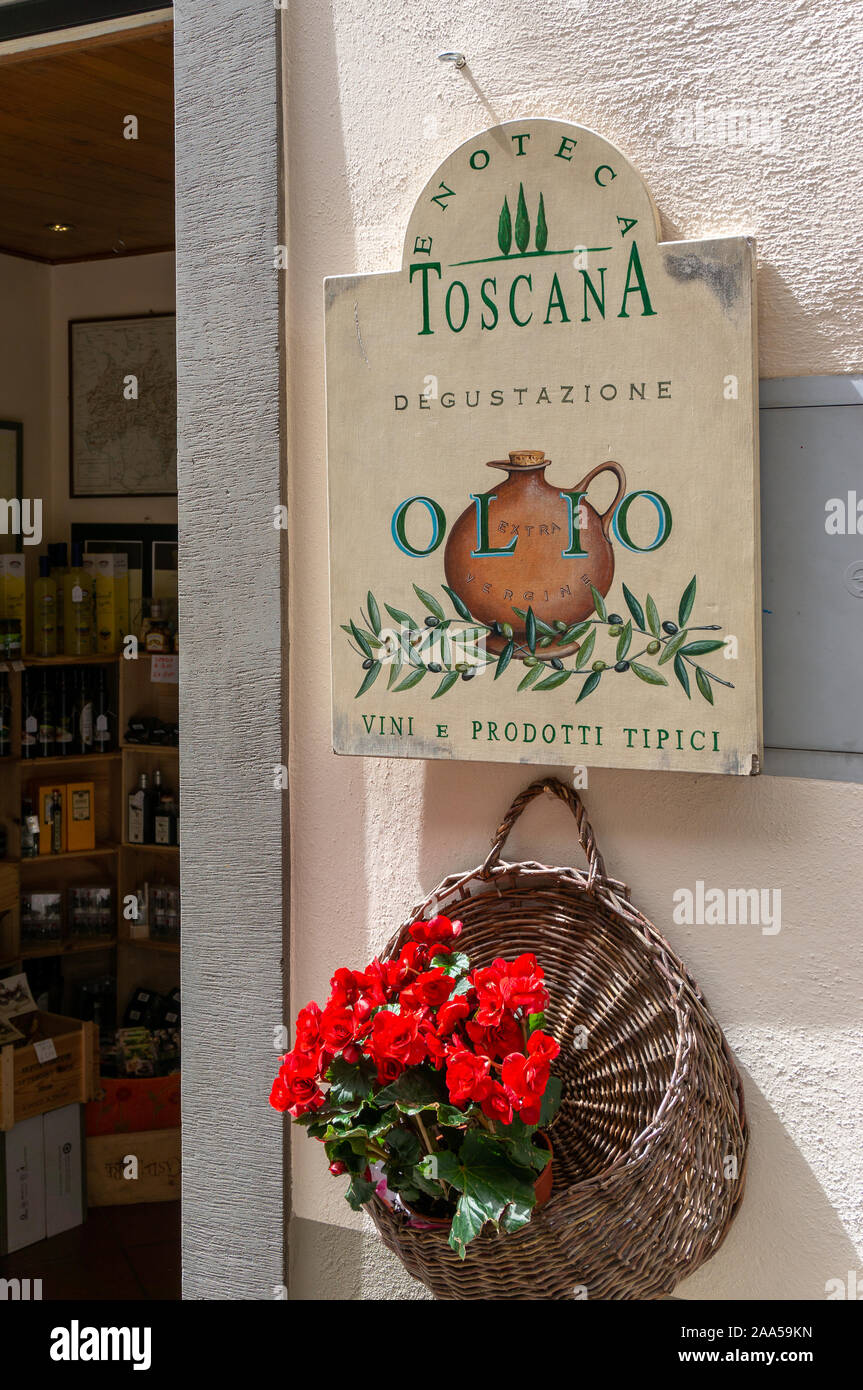 Les fleurs rouges et panier en osier pendre hors entrée de Enoteca, Radda in Chianti, Toscane, Italie Banque D'Images