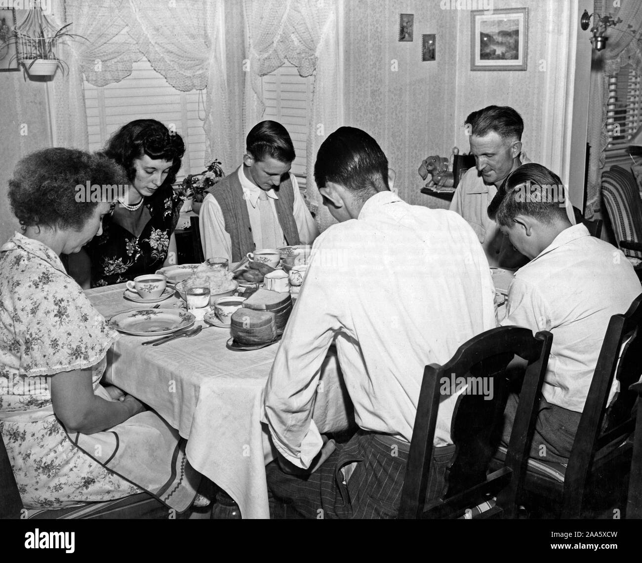 Env : fin des années 50 ou au début des années 1960, la famille d'un conducteur de camion vit une vie semblable à celle des autres travailleurs américains. Cette famille à Arlington Virginia baissent la tête dans la prière avant de manger leur repas du soir. Banque D'Images