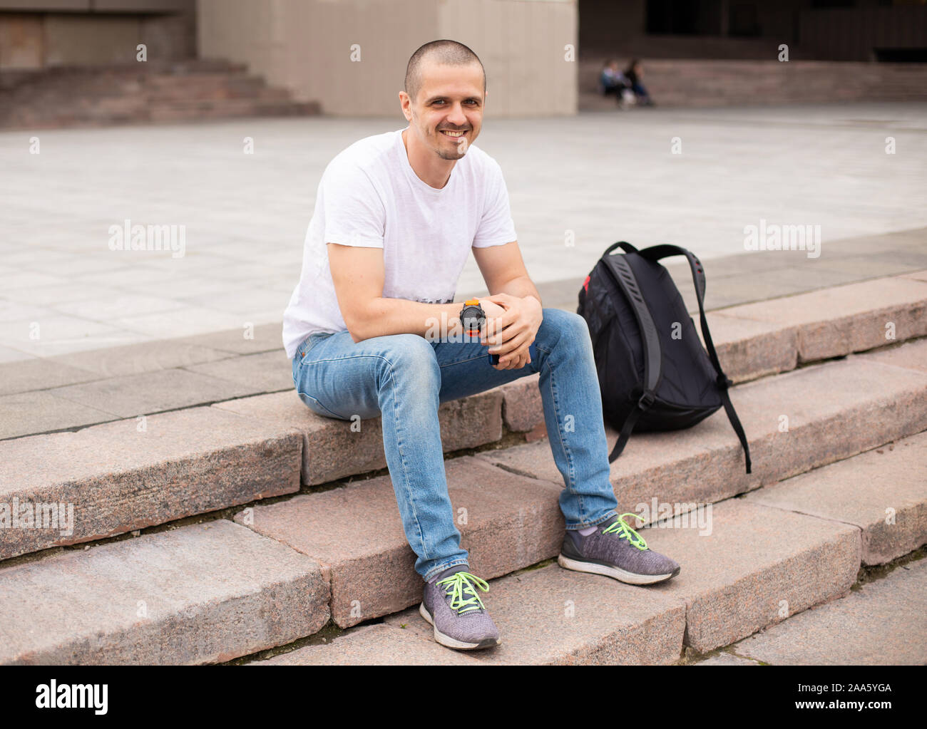 L'homme à la caméra en souriant et en étant assis sur des escaliers Banque D'Images