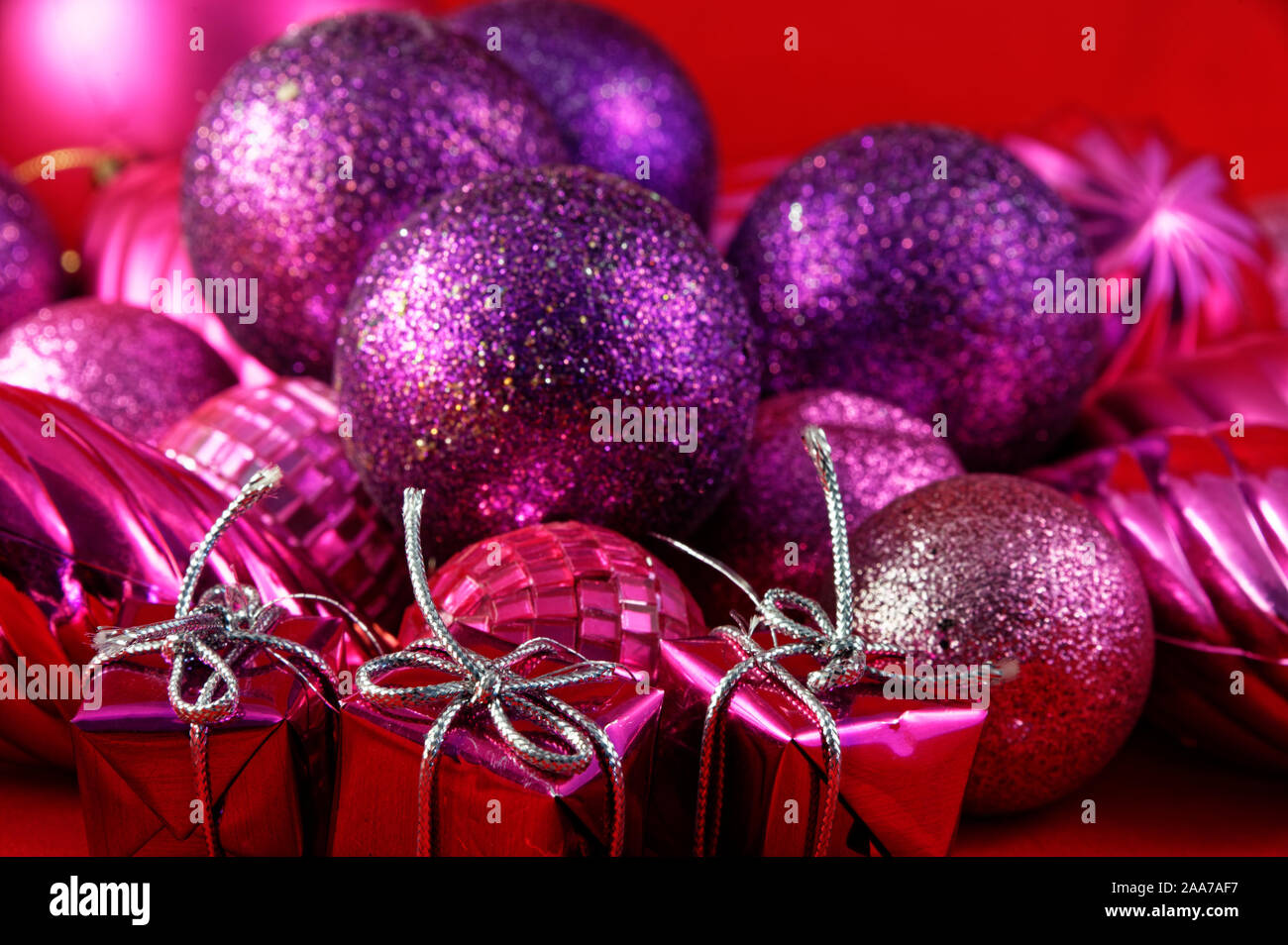 Cadeaux en boîte avec de l'argent liée string s'asseoir en face de violet et rose boules de Noël Banque D'Images