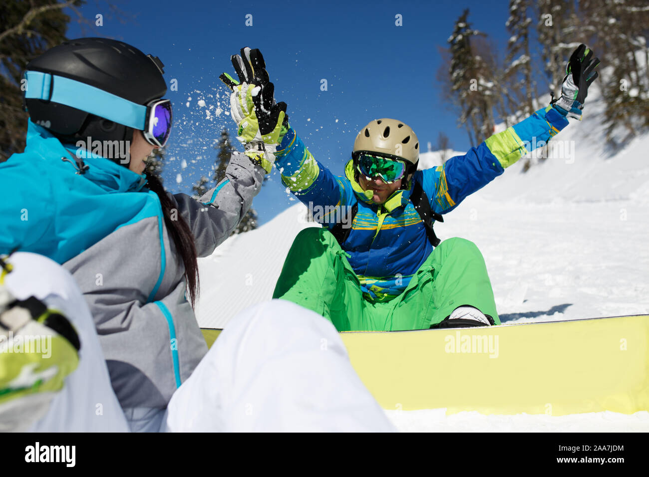 Woman doing handshake with happy man with snowboard assis sur le flanc de la journée d'hiver Banque D'Images