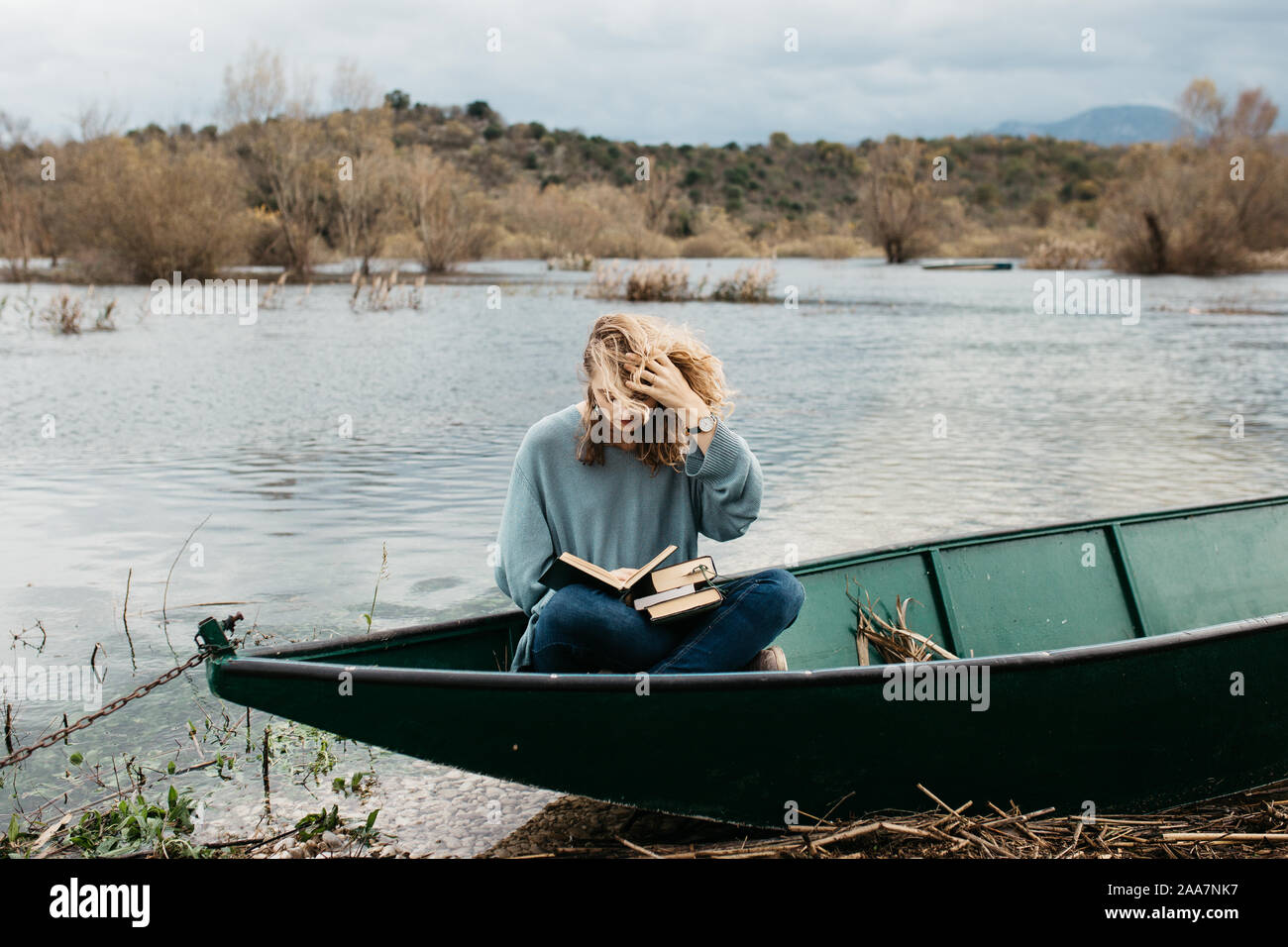 Portrait de la jeune belle femme assise sur un bateau et lecture d'un livre. Elle est bookworm et elle choisit entre quelques livres. Banque D'Images