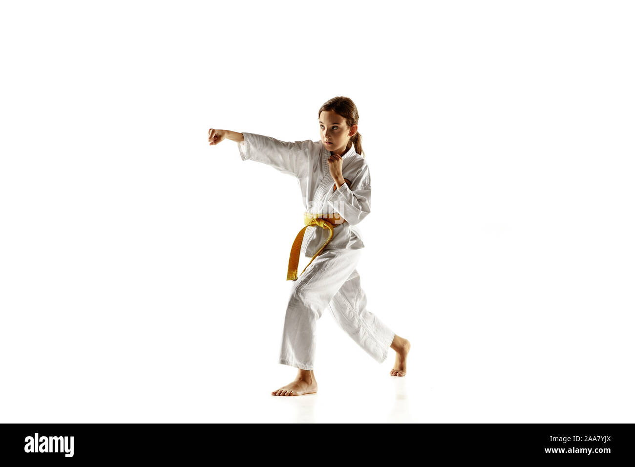 Confiant dans la catégorie junior en kimono pratiquer le combat corps à corps, les arts martiaux de jeunes femelles fighter avec ceinture jaune s formation sur fond studio blanc. Concept de vie sain, le sport, l'action. Banque D'Images