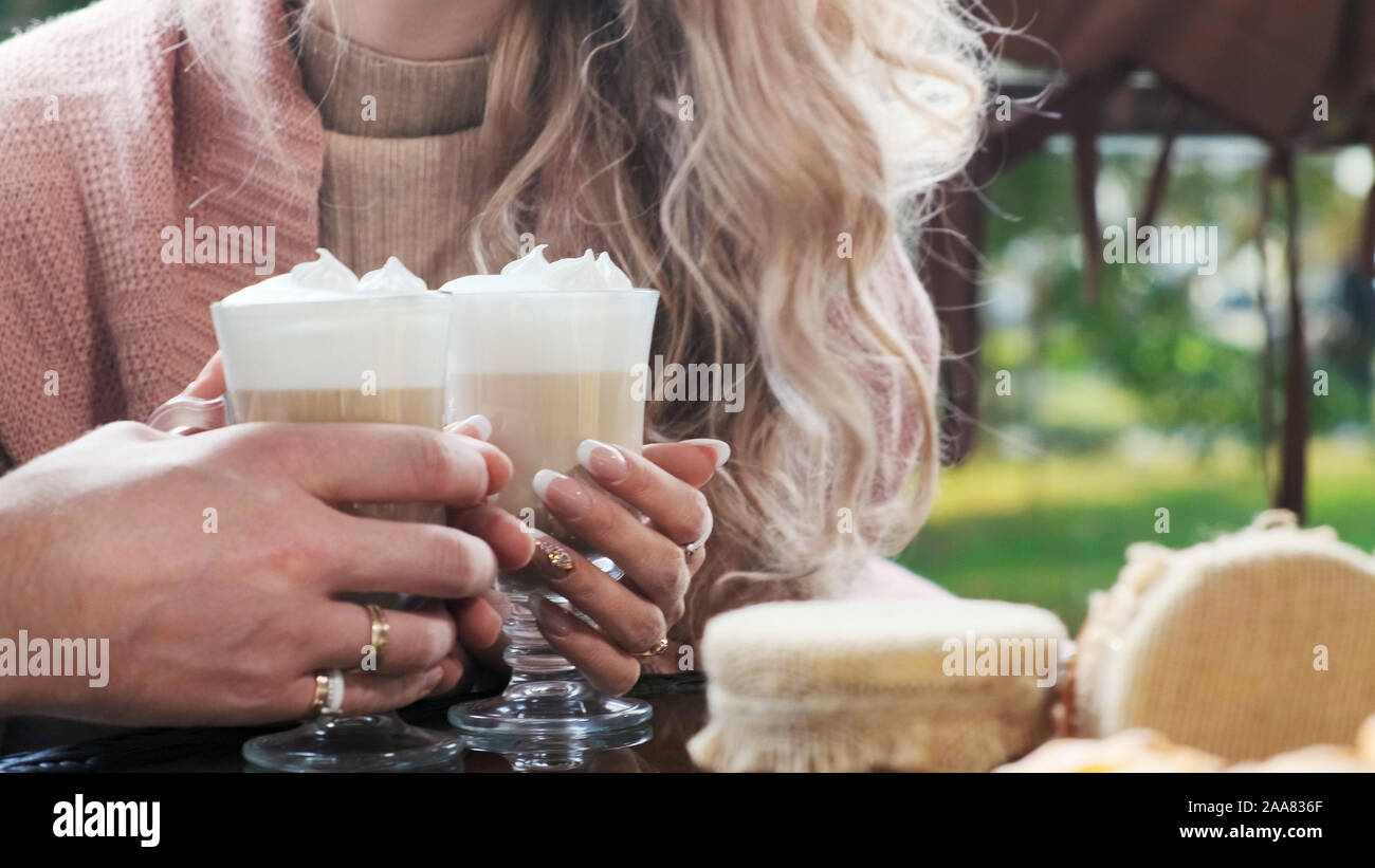 Couple dans un café sur la terrasse. Close-up mains des amoureux l'homme et la femme tenir les tasses avec du cappuccino et latte Banque D'Images