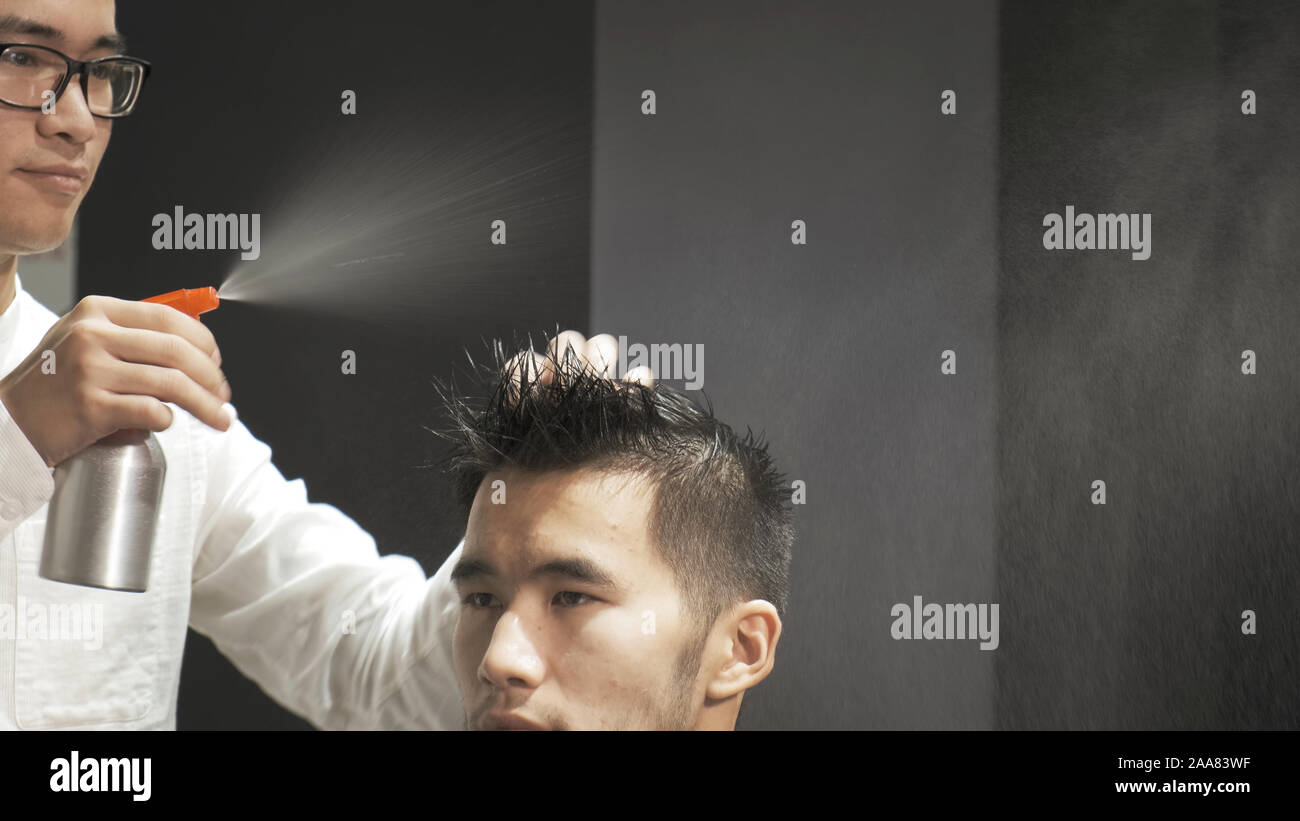 Asian male devient une coupe moderne dans barber shop. Coiffure cheveux mouille en pulvérisation et les peignes. Banque D'Images