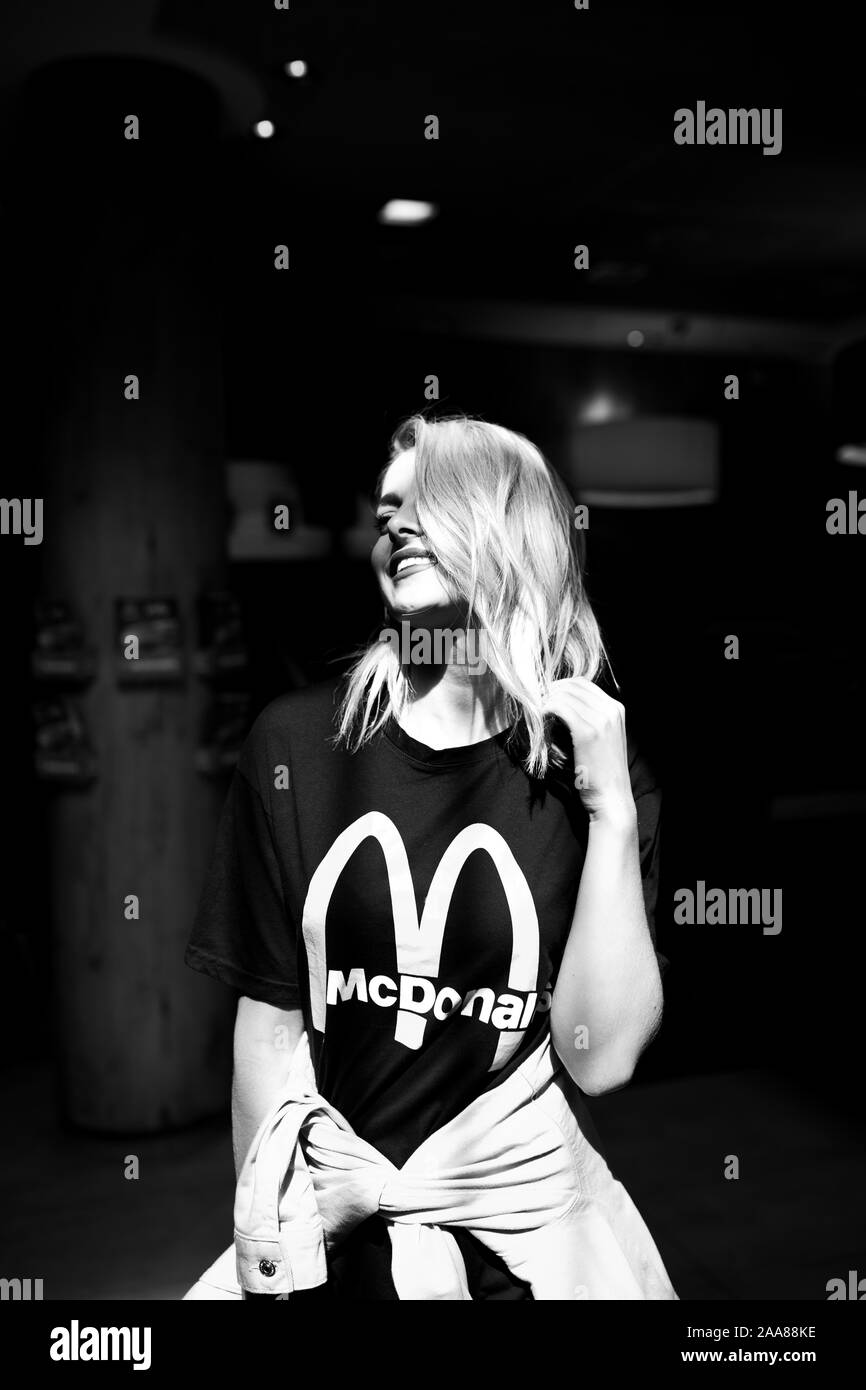 Le noir et blanc portrait of happy young woman. Elle pose à l'intérieur de la société MCDonald's à Sarajevo. Elle est aussi le port de McDonald's t shirt. Août, 2019 Banque D'Images