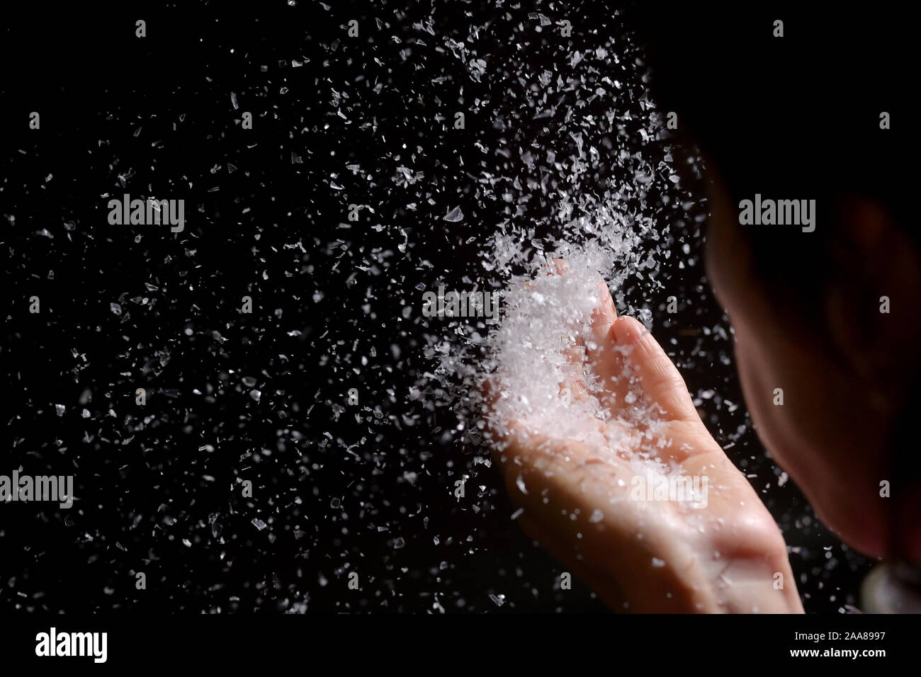 Woman Blowing de neige artificielle dans le noir Banque D'Images